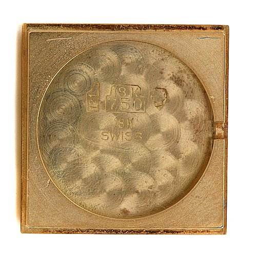 This image shows the underside of the case back of a Cartier Tank Classic Women's Yellow Gold White Dial Women's Yellow Gold White Dial model watch, featuring engravings indicating it's 18K gold and Swiss-made.