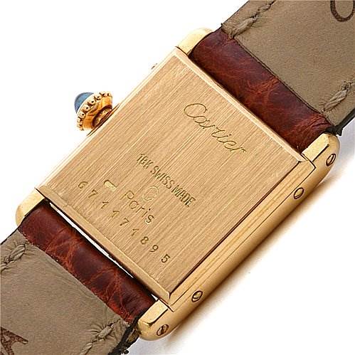 The image shows the back case of a Cartier Tank Classic Women's Yellow Gold White Dial Women's Yellow Gold White Dial watch, along with parts of its brown leather strap.