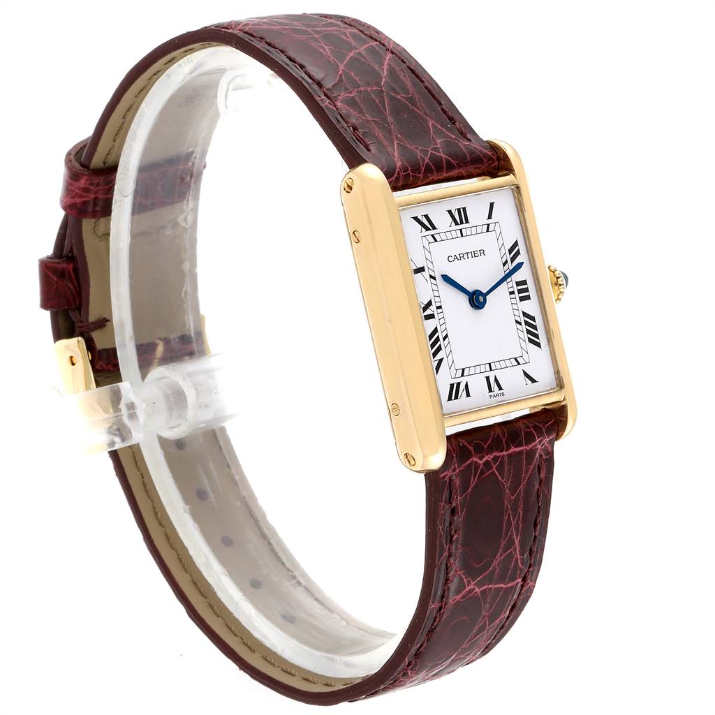 This image shows a Cartier Tank Classic Women's Yellow Gold White Dial Women's Yellow Gold White Dial watch at an angle highlighting the face, gold rectangular case, and maroon leather strap.