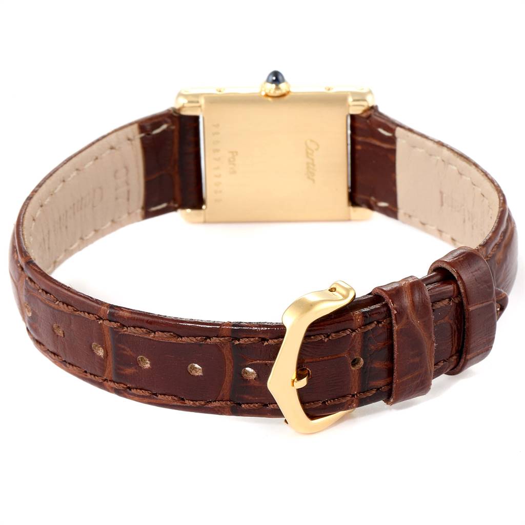 The image shows the back view of the Tank Classic model by Cartier with a brown leather strap and gold buckle.