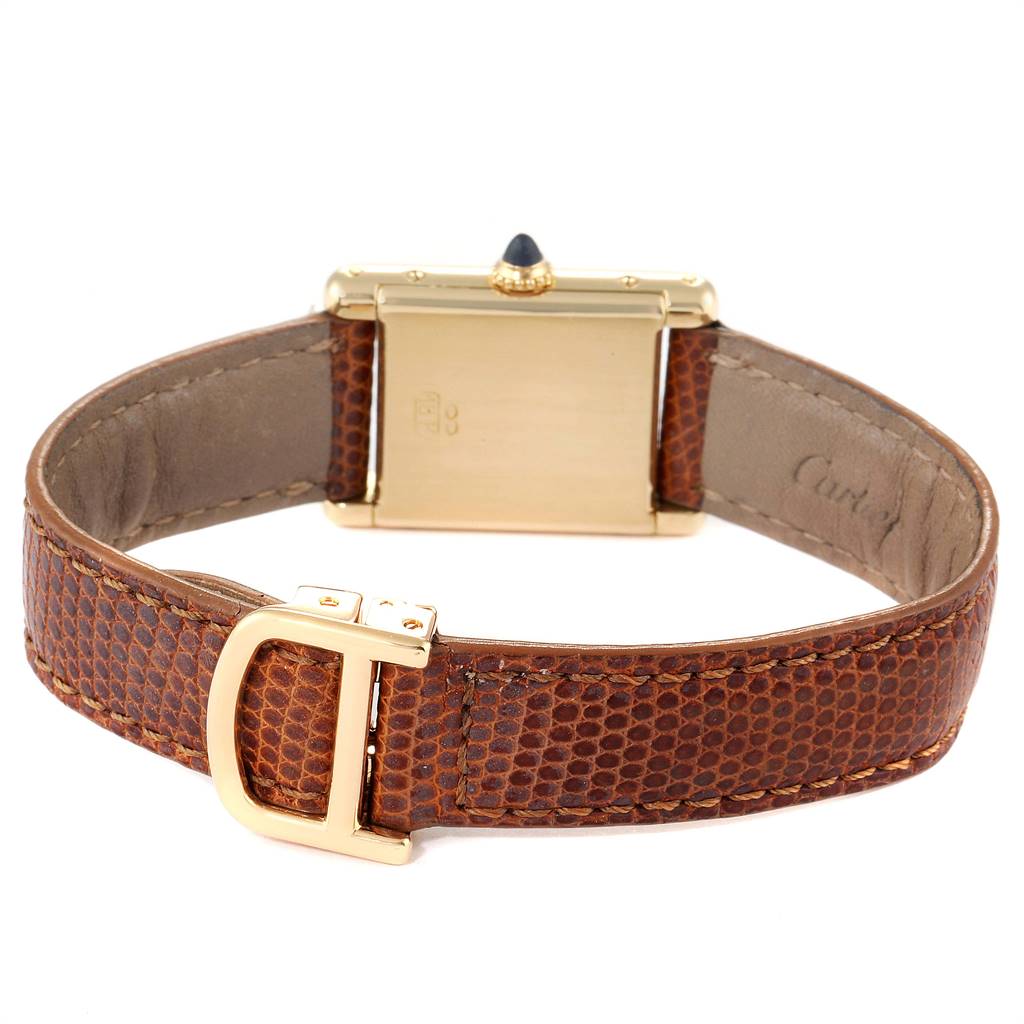 The image shows the back of a Cartier Tank Classic Women's Yellow Gold White Dial Women's Yellow Gold White Dial model watch, highlighting the gold case, crown, and brown leather strap with a gold clasp.