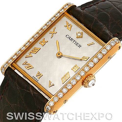 The image showcases an angled close-up of the Cartier Tank Classic C70934 Yellow Gold Silver Dial C70934 Yellow Gold Silver Dial watch, highlighting its diamond-set bezel, Roman numeral dial, and crown detail.