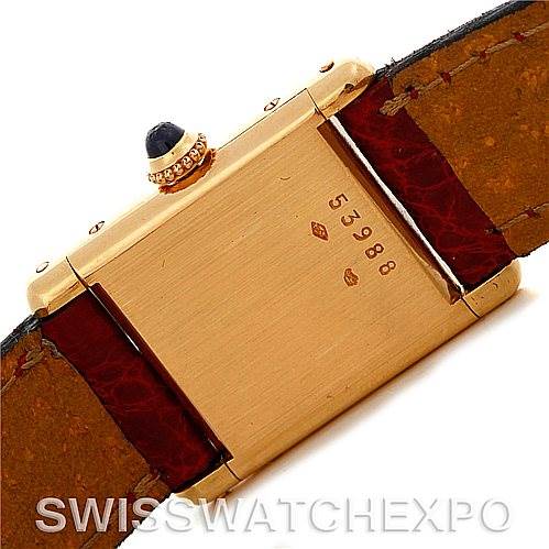 The image shows the back of a Cartier Tank Classic Women's Yellow Gold White Dial Women's Yellow Gold White Dial watch, highlighting the gold case, serial number, and leather straps.