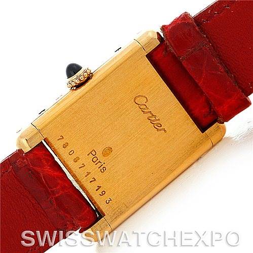 This image shows the back case of a Cartier Tank Classic Women's Yellow Gold White Dial Women's Yellow Gold White Dial watch with a red leather strap.
