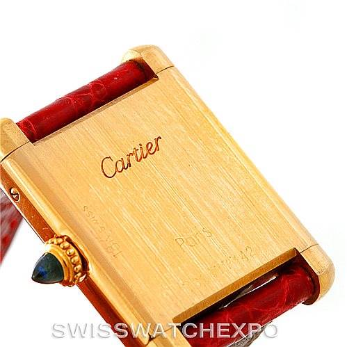 This image shows the back case and crown of a Cartier Tank Classic Women's Yellow Gold White Dial Women's Yellow Gold White Dial watch, with a partial view of the red leather strap.