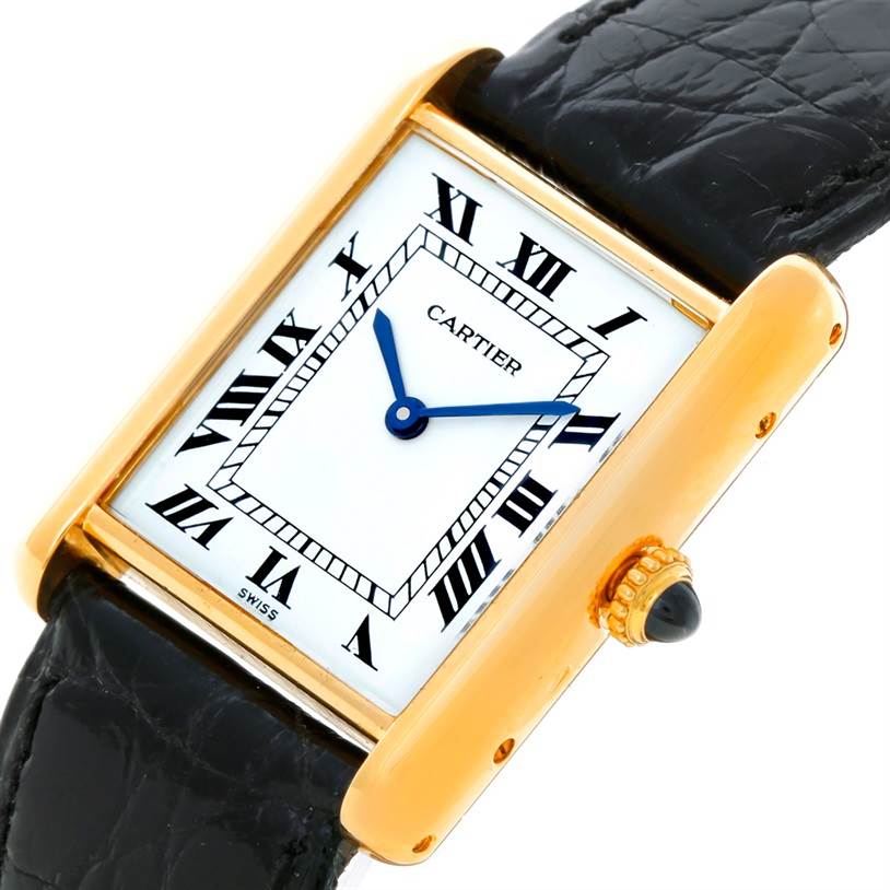 The Cartier Tank Classic Yellow Gold White Dial Yellow Gold White Dial watch is shown at an angle showcasing the face, Roman numeral dial, and side view of the gold case and black leather strap.