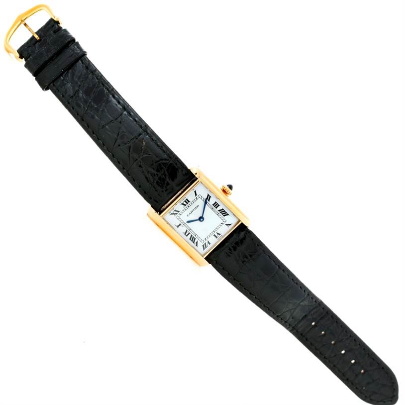 The Cartier Tank Classic Yellow Gold White Dial Yellow Gold White Dial watch is shown from a top-down angle, featuring its rectangular face and black leather strap.