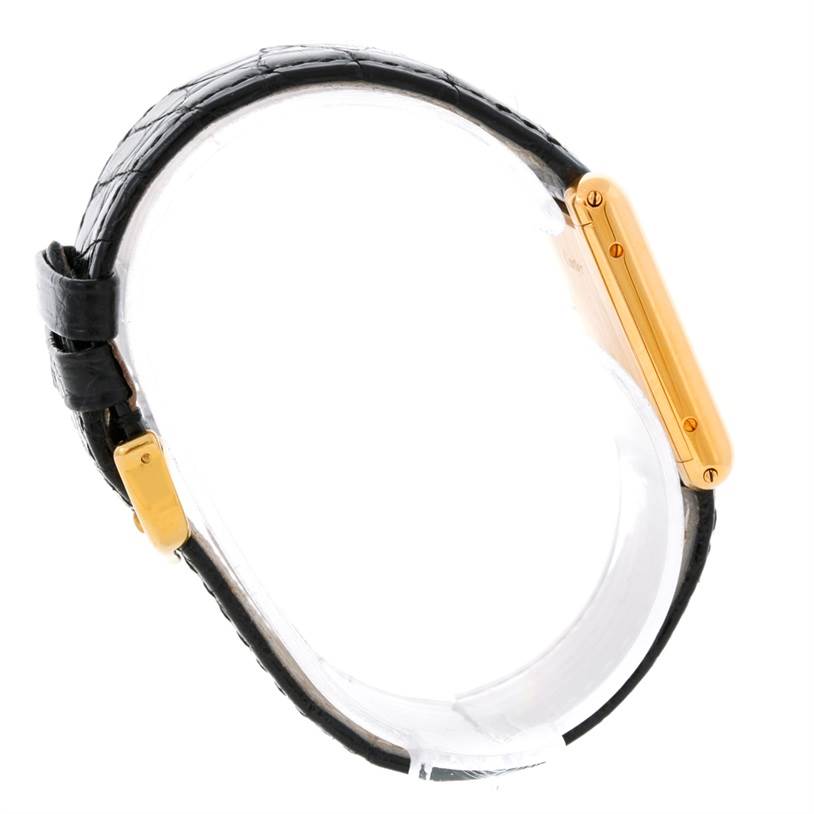 The image shows a side view of the Tank Classic watch by Cartier, highlighting its black leather strap and gold case.