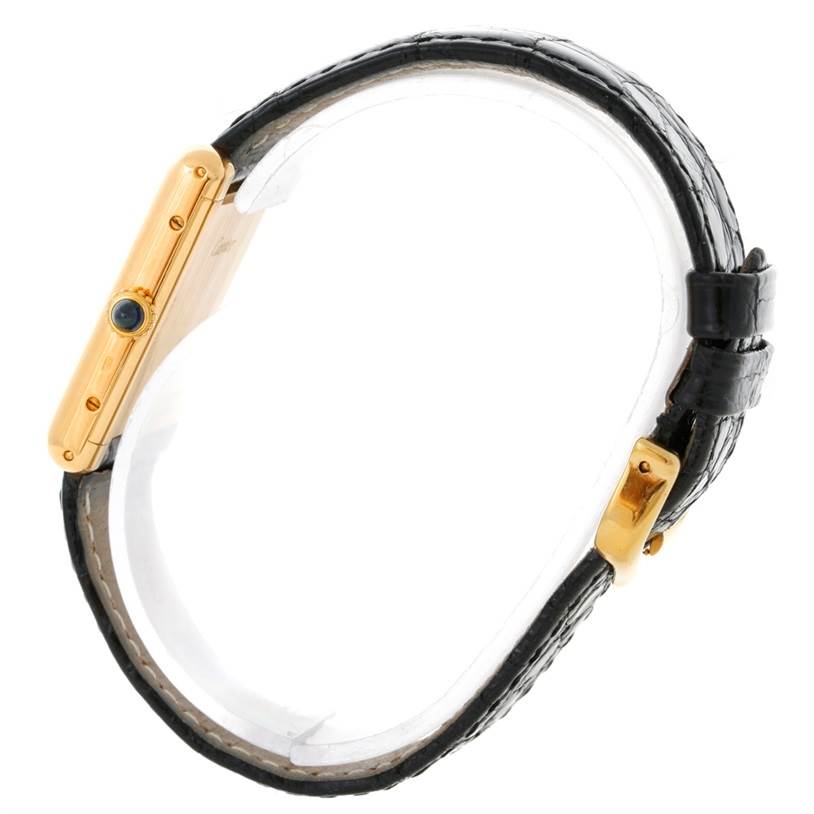 The image shows a side view of the Cartier Tank Classic Yellow Gold White Dial Yellow Gold White Dial watch, highlighting its gold case, black leather strap, and crown.