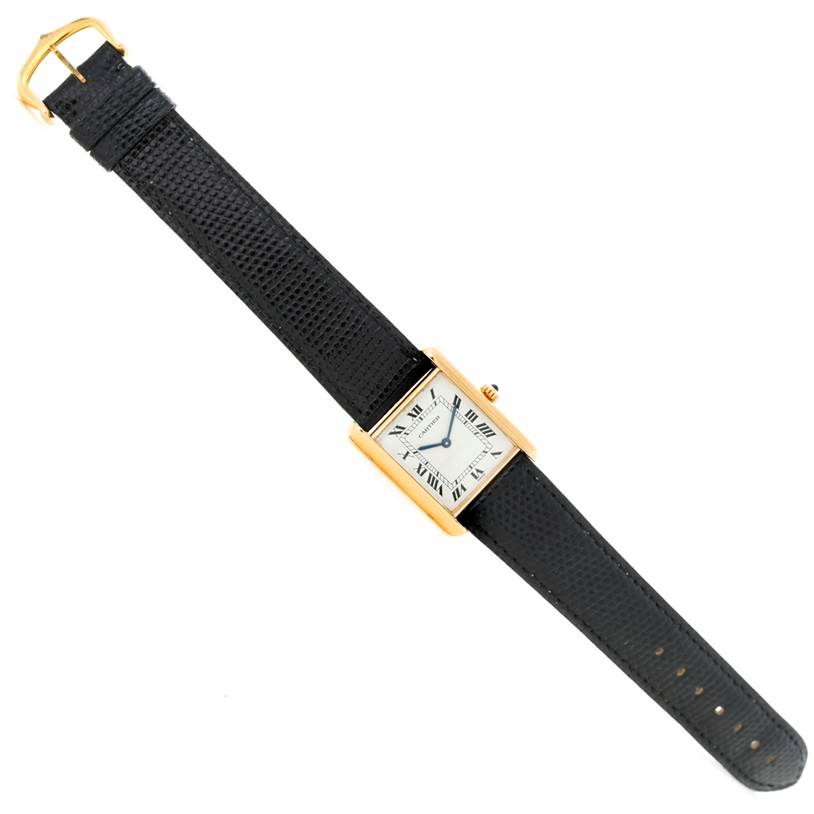 The image shows a top-down view of the Cartier Tank Classic Yellow Gold Beige Dial Yellow Gold Beige Dial watch, highlighting its black strap and rectangular dial.