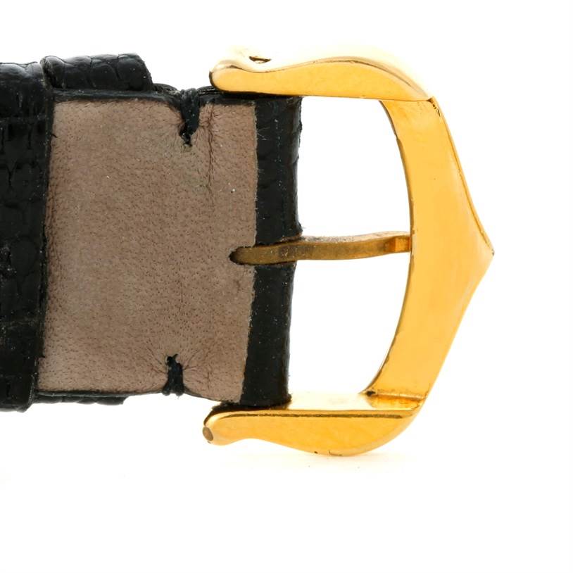 This image shows a close-up of the gold buckle and part of the black leather strap of a Cartier Tank Classic Yellow Gold Beige Dial Yellow Gold Beige Dial watch.