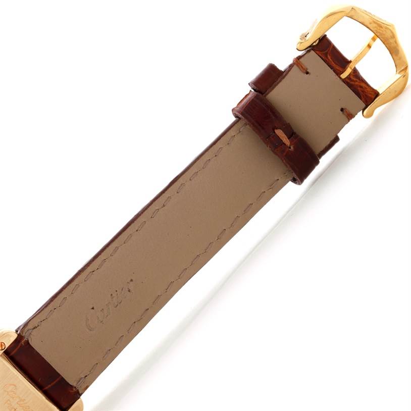 The image shows the underside of the leather strap and gold buckle of a Cartier Tank Classic Women's Yellow Gold Silver Dial Women's Yellow Gold Silver Dial watch from a top-down angle.