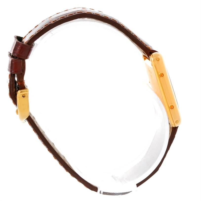 This side-angle view of the Cartier Tank Classic Women's Yellow Gold Silver Dial Women's Yellow Gold Silver Dial watch shows the gold case and brown leather strap.