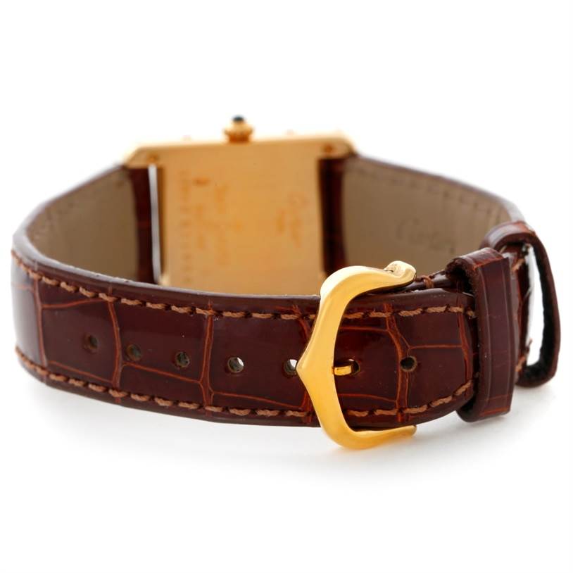 The image shows the back of the Tank Classic model watch by Cartier, focusing on the leather strap and gold buckle.