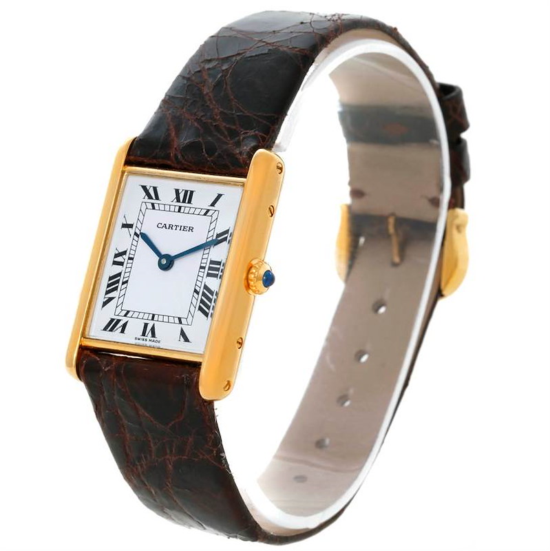 The Cartier Tank Classic watch is shown at an angled view, displaying the rectangular dial, Roman numerals, gold case, and brown leather strap.