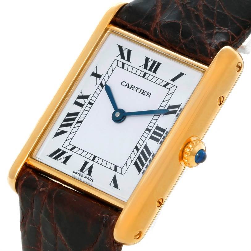 The Cartier Tank Classic 8810527329 Yellow Gold White Dial 8810527329 Yellow Gold White Dial watch is shown from an angled view, highlighting its rectangular face, gold casing, blue hands, and leather strap.