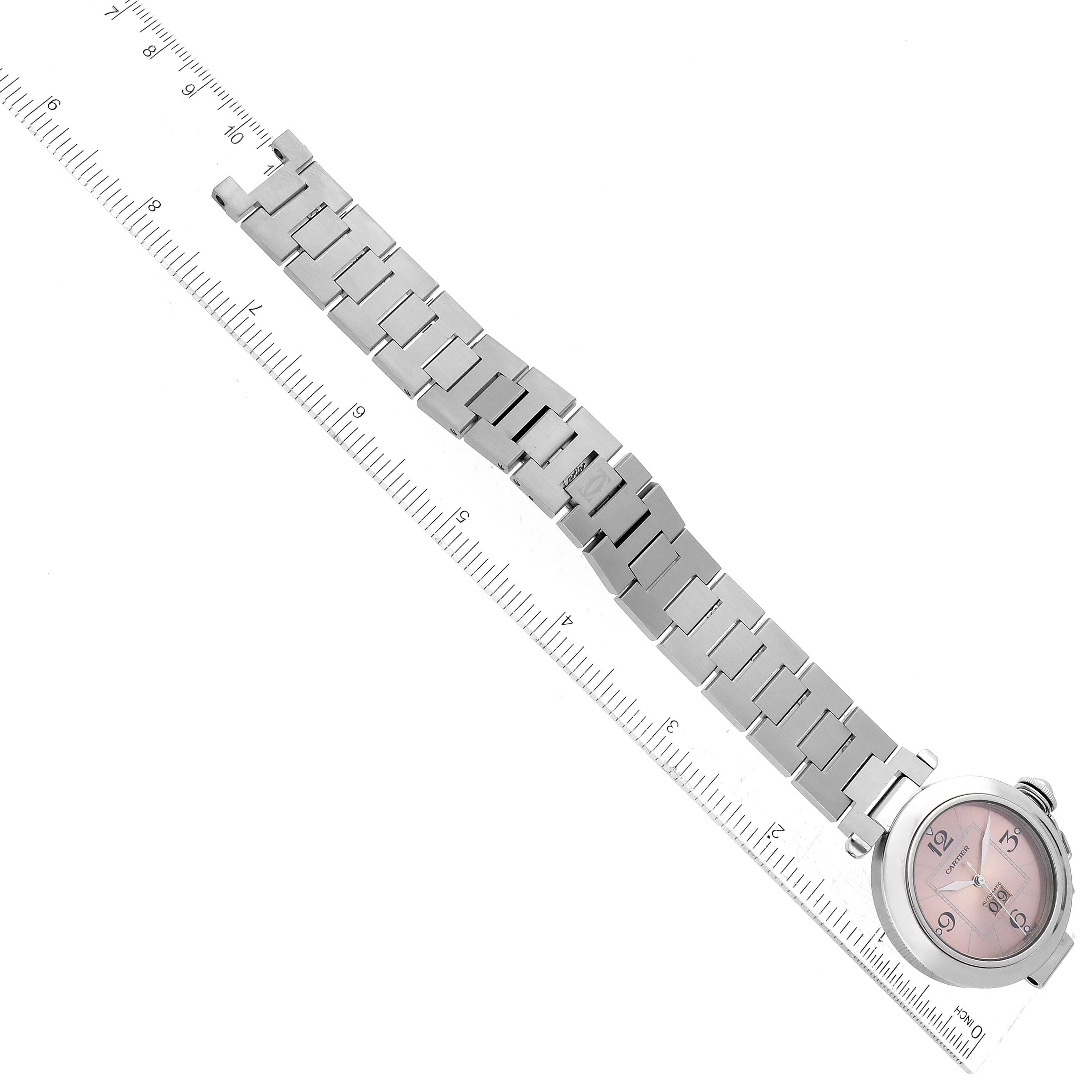 The image shows a Cartier Pasha W31058M7 Women's Stainless Steel Pink Dial W31058M7 Women's Stainless Steel Pink Dial watch at an angled top-down view, displaying the watch face and metal bracelet alongside a ruler for scale.