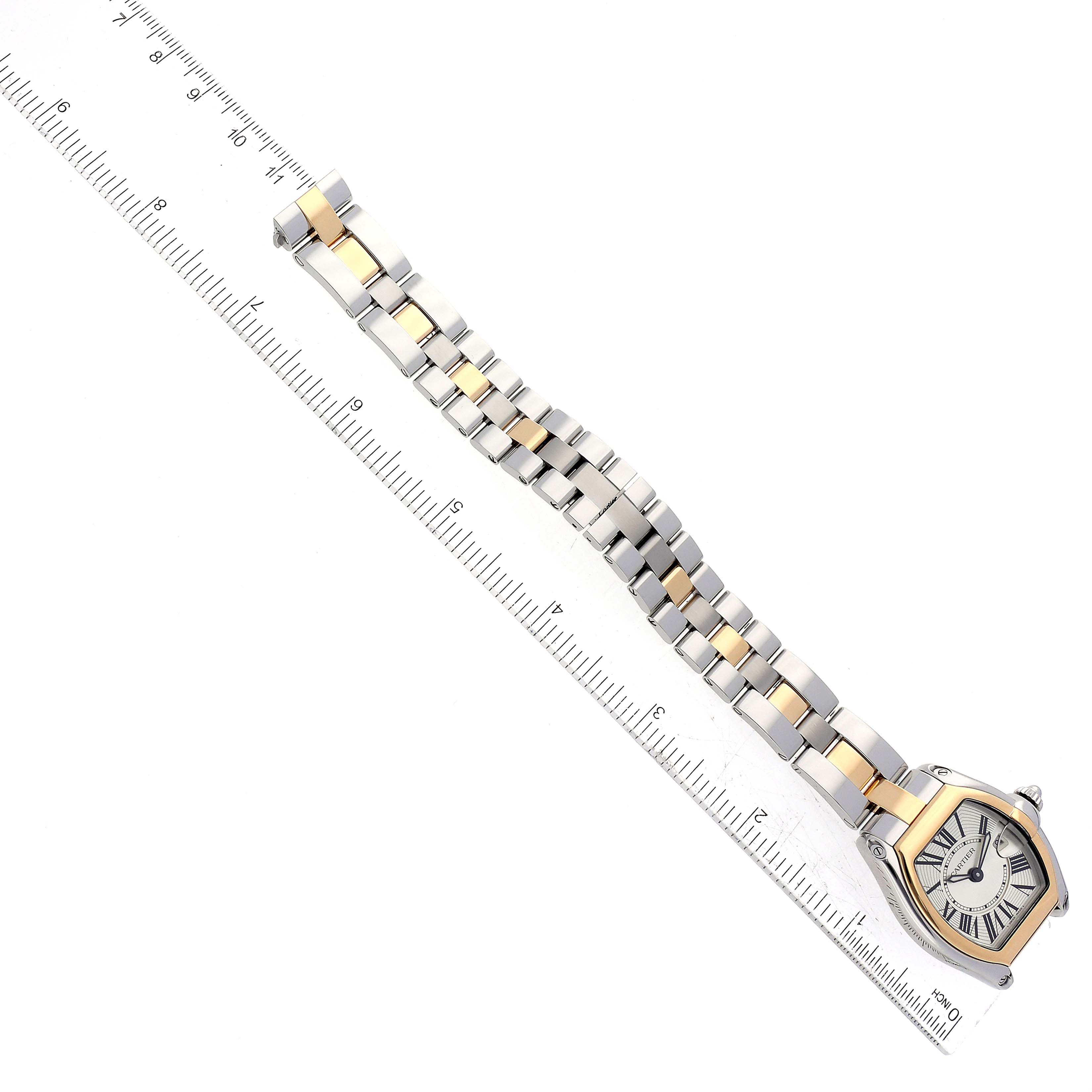 The Cartier Roadster W62026Y4 Women
s Steel and Gold (two tone) Silver Dial W62026Y4 Women
s Steel and Gold (two tone) Silver Dial watch is shown from a top-down angle, featuring its face and band next to a ruler for scale.