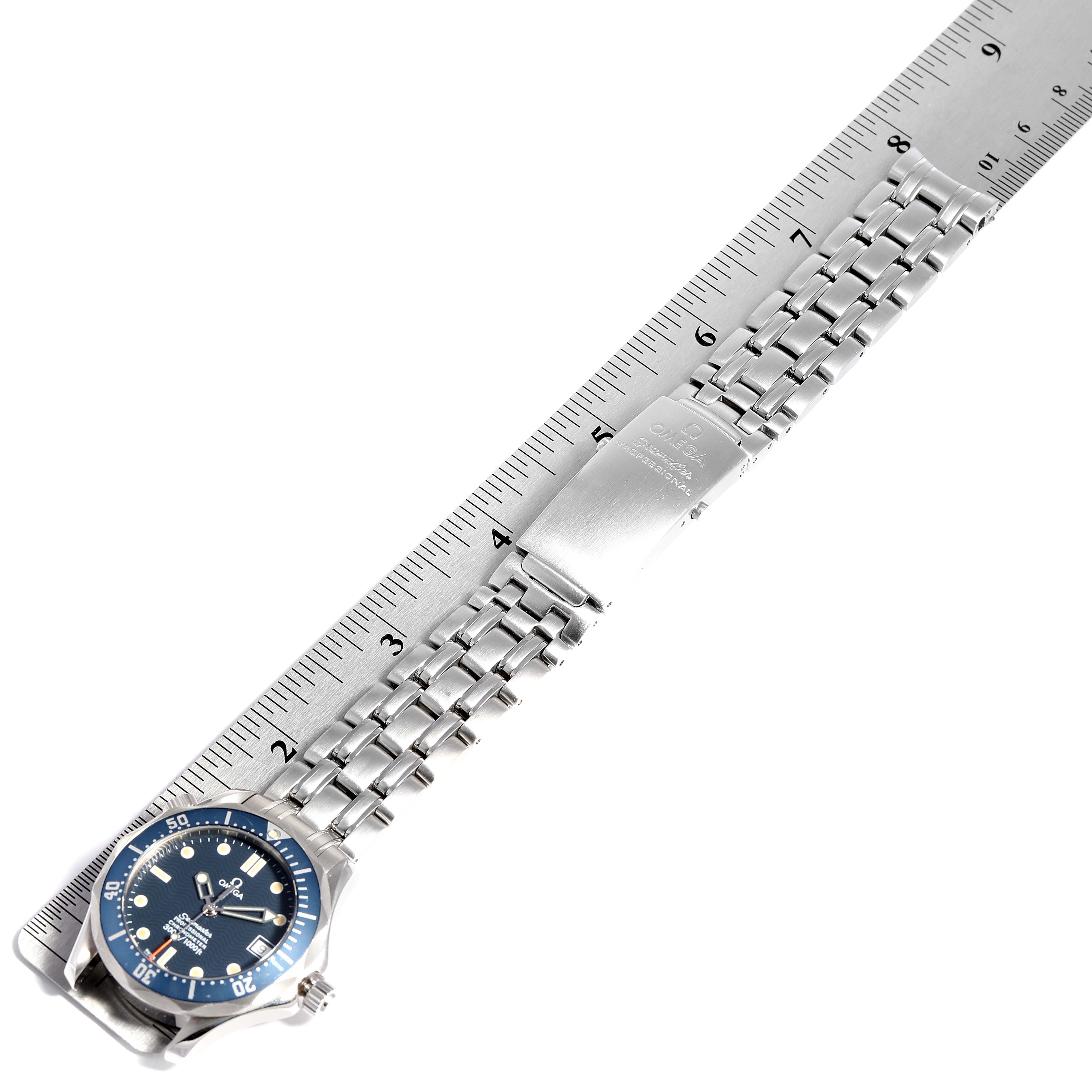 The image shows an Omega Seamaster 2551.80.00 Men
s Stainless Steel Blue Dial 2551.80.00 Men
s Stainless Steel Blue Dial watch and metal bracelet flat against a ruler, highlighting its clasp and face.