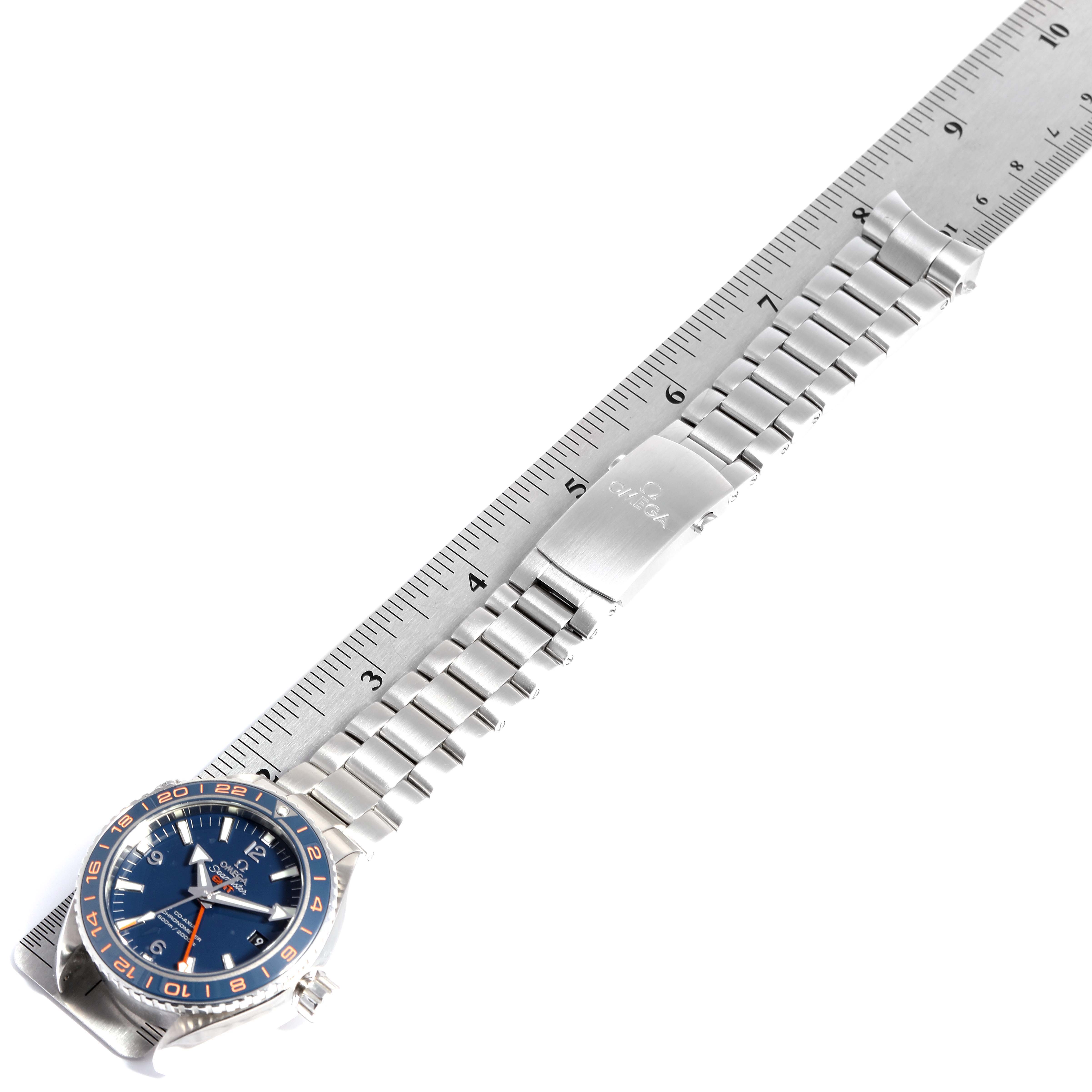 The image shows the Omega Planet Ocean 232.30.44.22.03.001 Men
s Stainless Steel Blue Dial 232.30.44.22.03.001 Men
s Stainless Steel Blue Dial watch laid flat from a top-down angle with its bracelet on a measuring ruler.