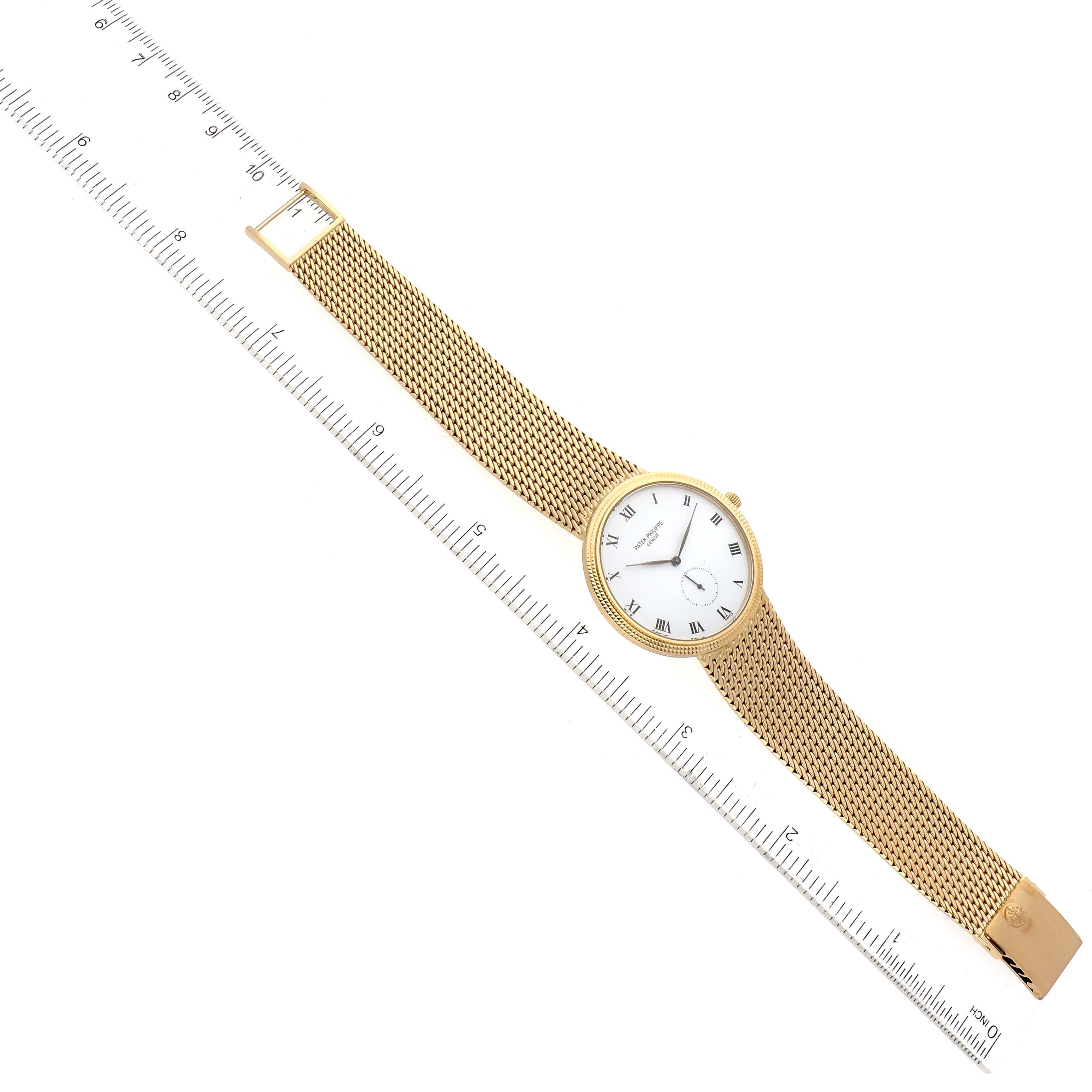 This image shows a Patek Philippe Calatrava 3919/5 Men
s Yellow Gold White Dial 3919/5 Men
s Yellow Gold White Dial watch, including its gold mesh bracelet and white dial with Roman numerals, next to a ruler.