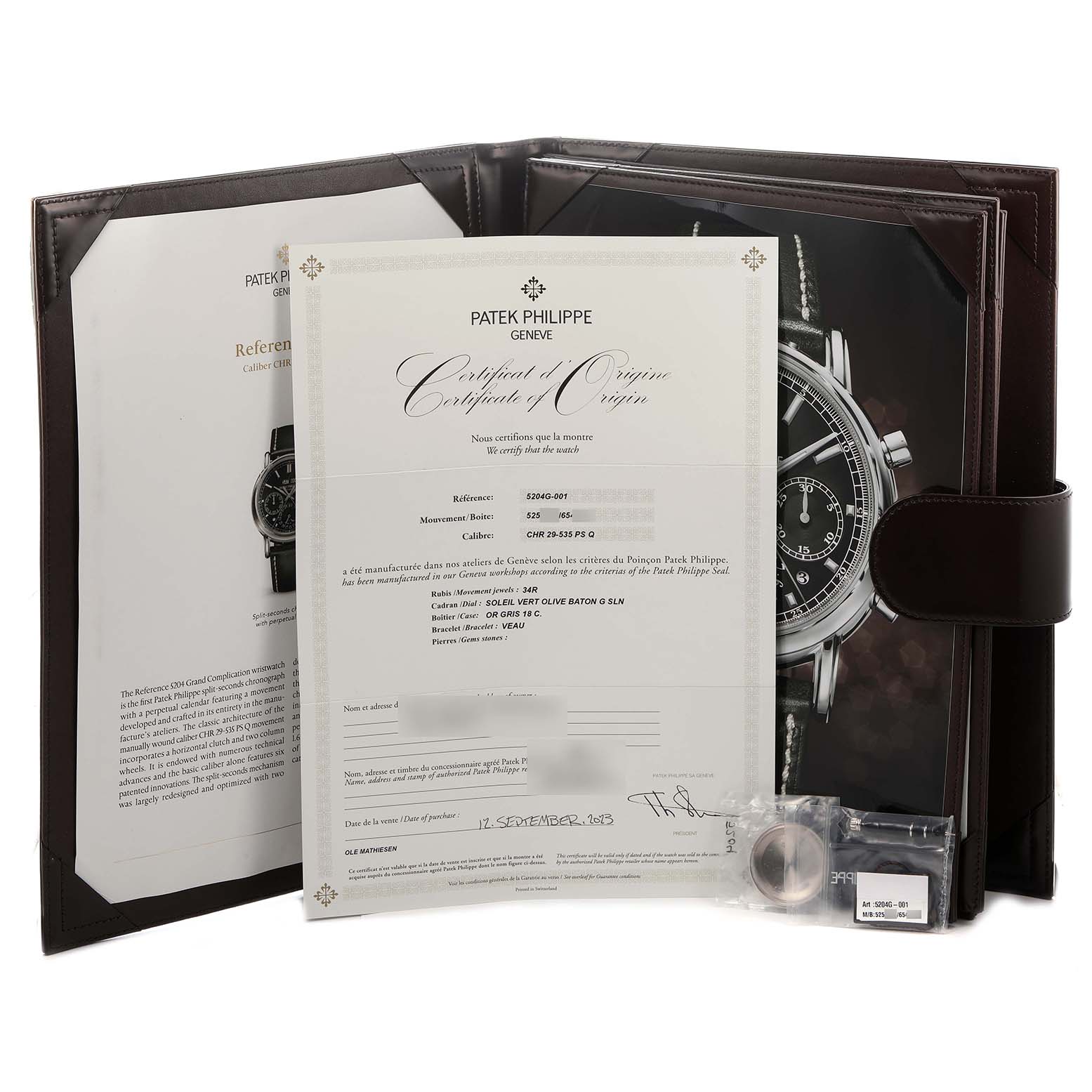 The image shows the Patek Philippe Complications model 5204G-001's certificate, booklet, and additional accessories inside a leather folder.
