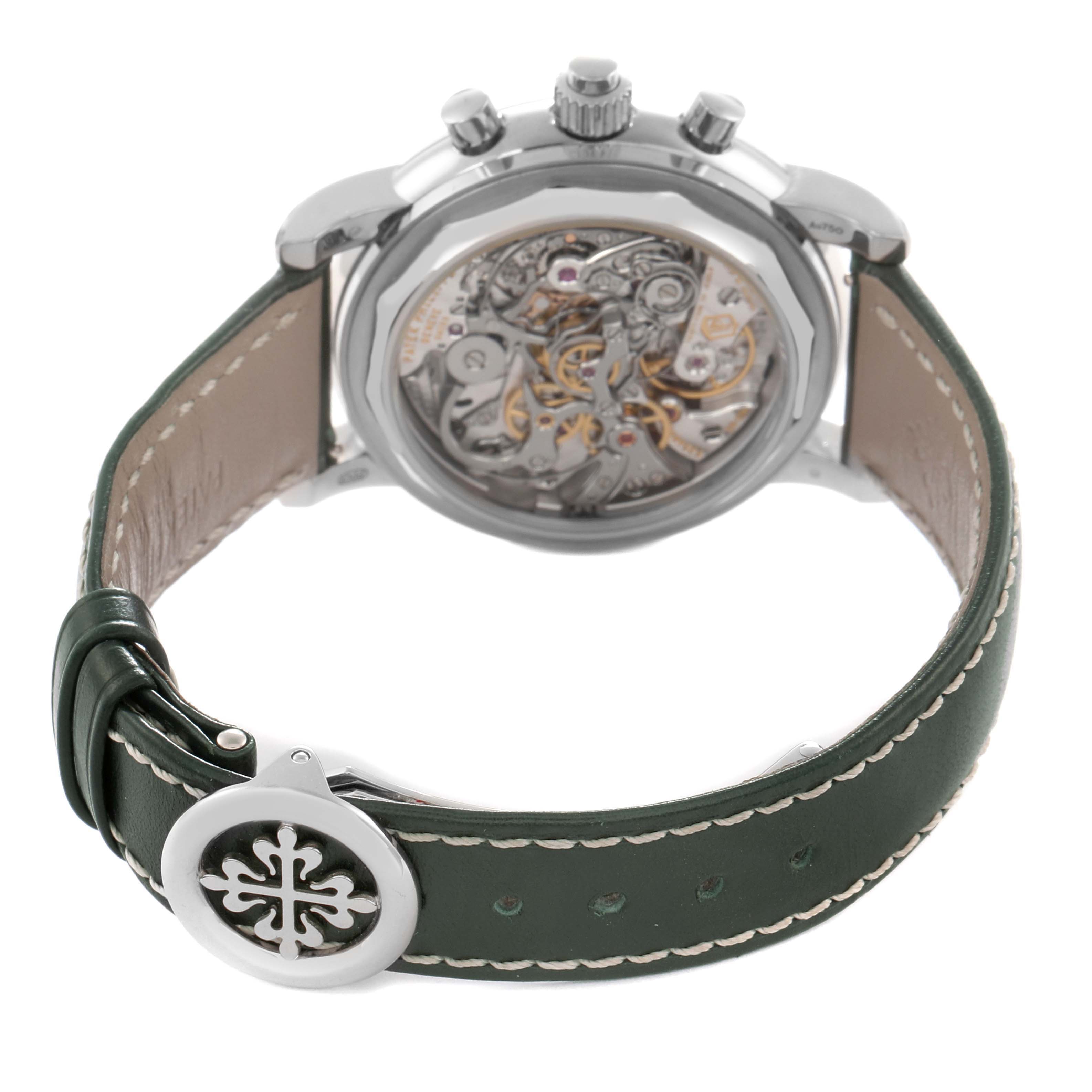 The image shows the back view of a Patek Philippe Complications model 5204G-001, highlighting the intricate mechanism and part of the leather strap with a decorative buckle.