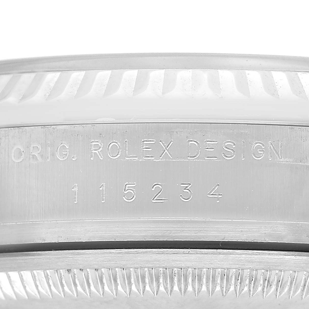 The image shows a close-up side view of a Rolex Datejust 115234 Men's Stainless Steel White Dial watch case with engraved text and serrated edges.