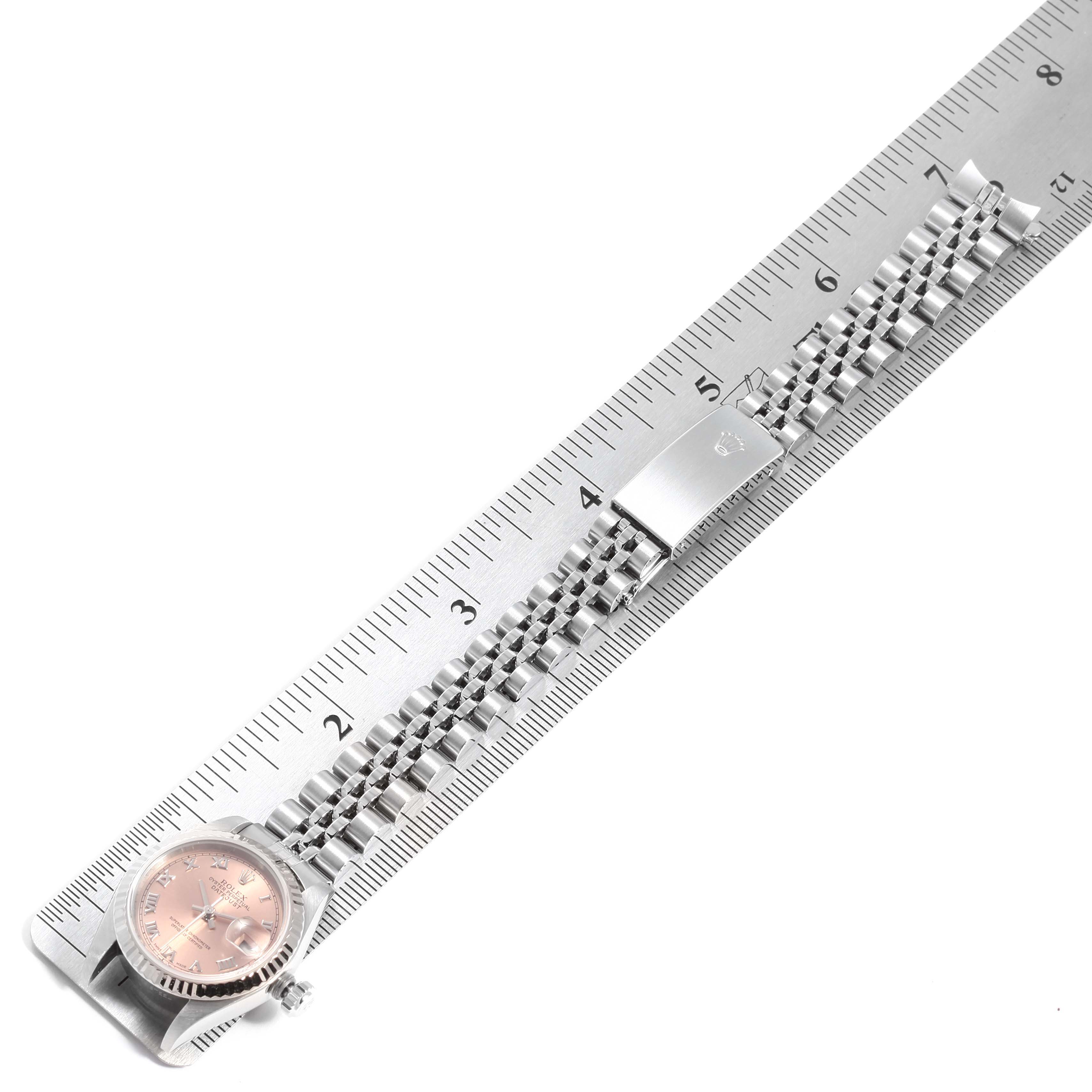 This image displays a Rolex Datejust 79174 Women's Stainless Steel Pink Dial 79174 Women's Stainless Steel Pink Dial watch laid flat beside a ruler, showing the watch face, bracelet, and clasp.