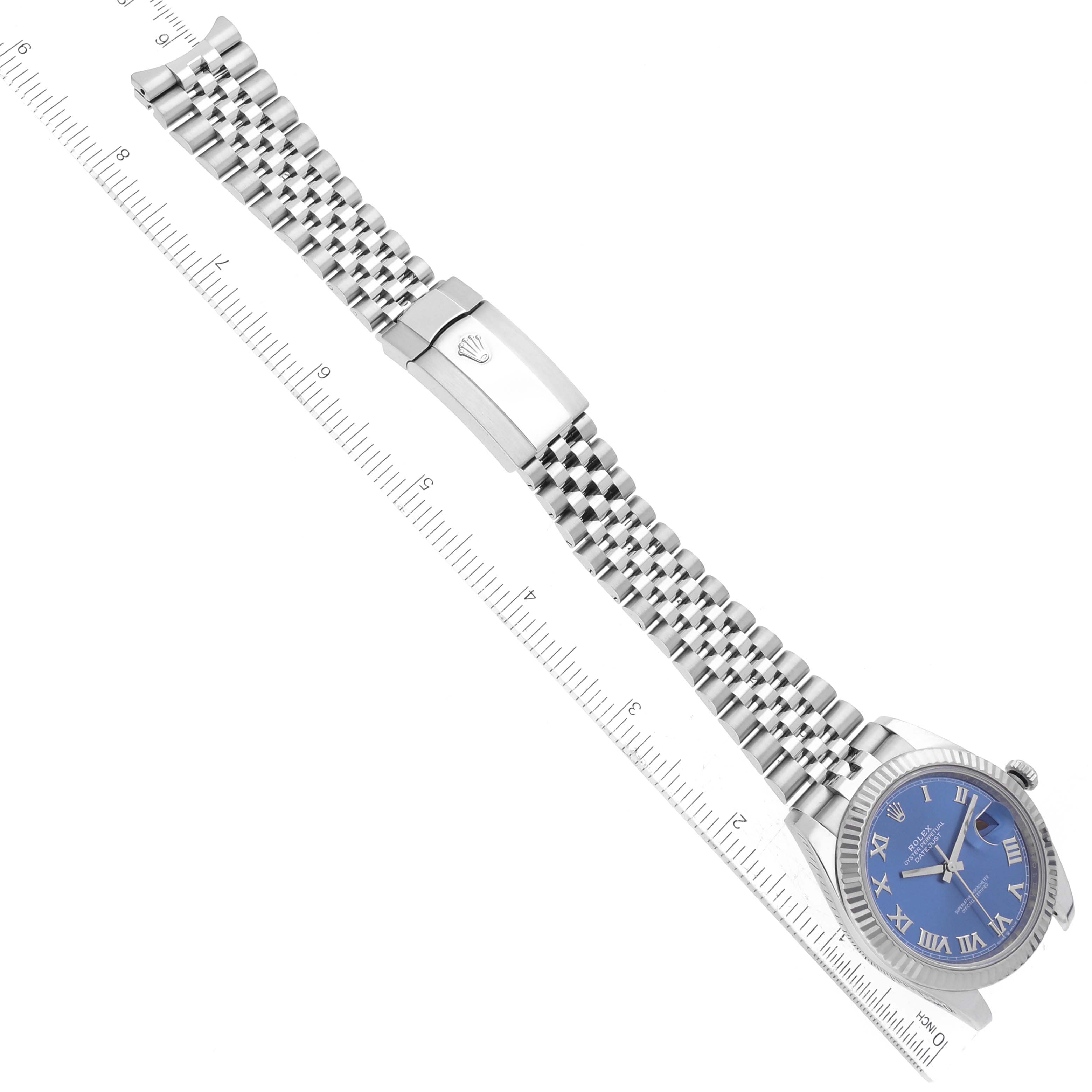 The image shows a Rolex Datejust 41 126334 Men
s Stainless Steel Blue Dial 126334 Men
s Stainless Steel Blue Dial watch from an angled top-down view, highlighting its blue dial and stainless steel bracelet with a ruler alongside.