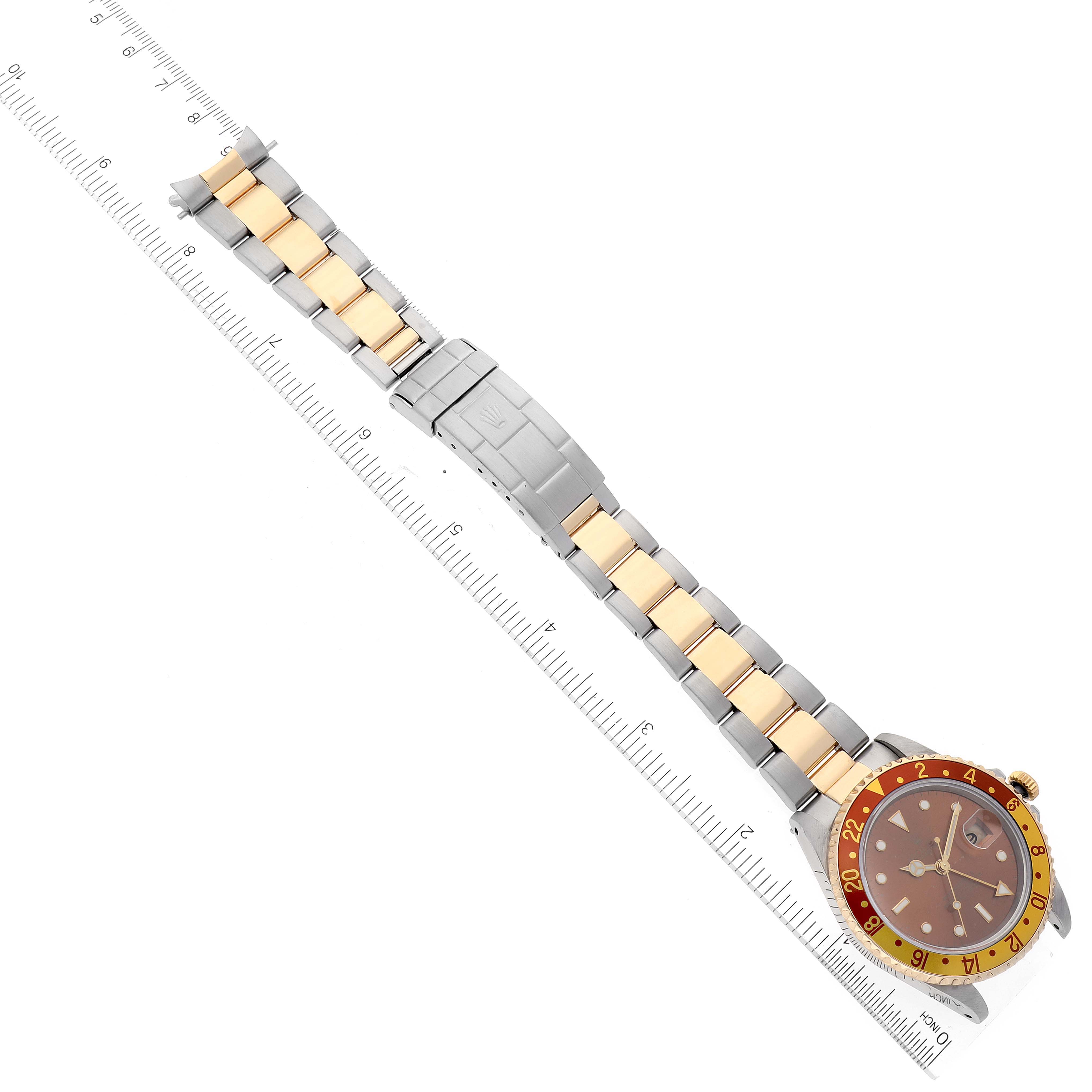 The image shows a top-down view of a Rolex GMT-Master 16713 Men's Steel and Gold (two tone) Brown Dial 16713 Men's Steel and Gold (two tone) Brown Dial watch with a two-tone bracelet and a ruler for scale.