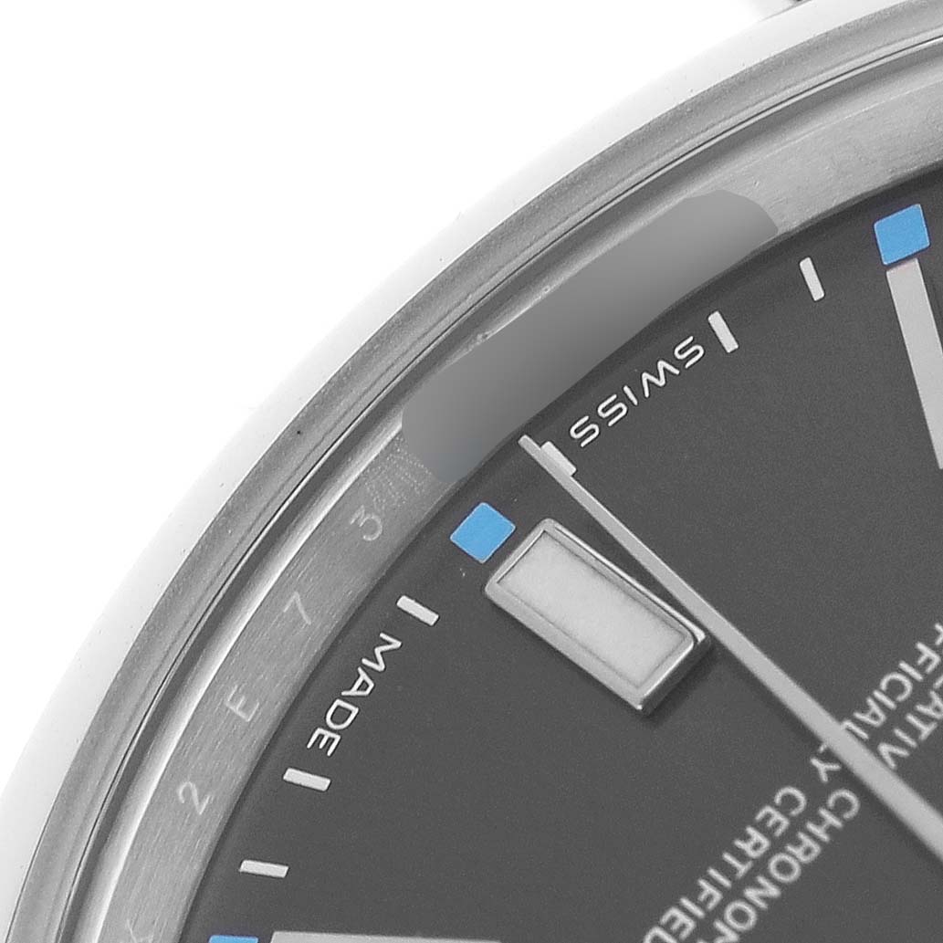 The image shows a close-up angle of the Rolex Oyster Perpetual 114300 Men's Stainless Steel Grey Dial watch's dial, focusing on the hour markers and part of the bezel.