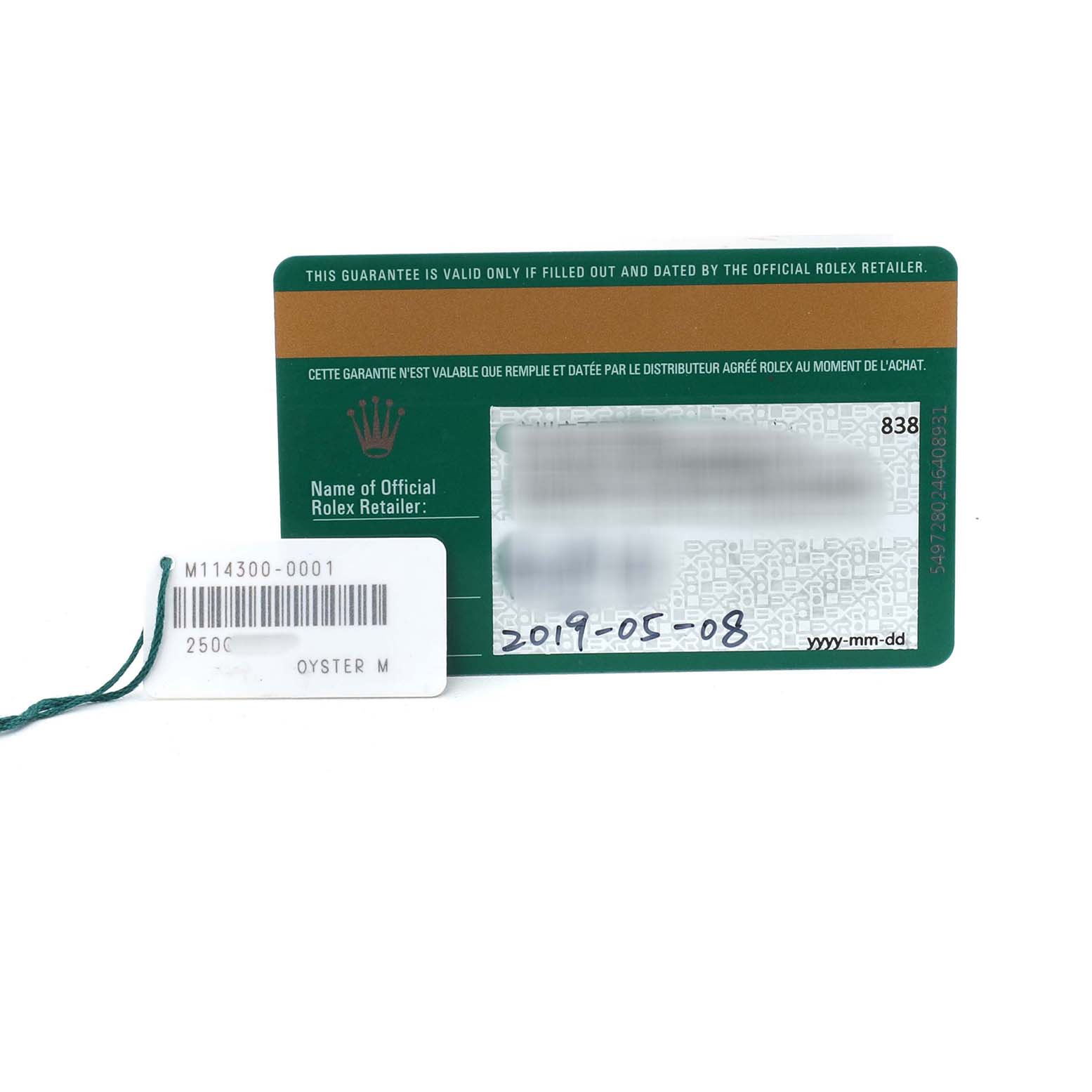 The image shows a warranty card for the Rolex Oyster Perpetual 114300 Men's Stainless Steel Grey Dial model, along with a tag bearing the model number.