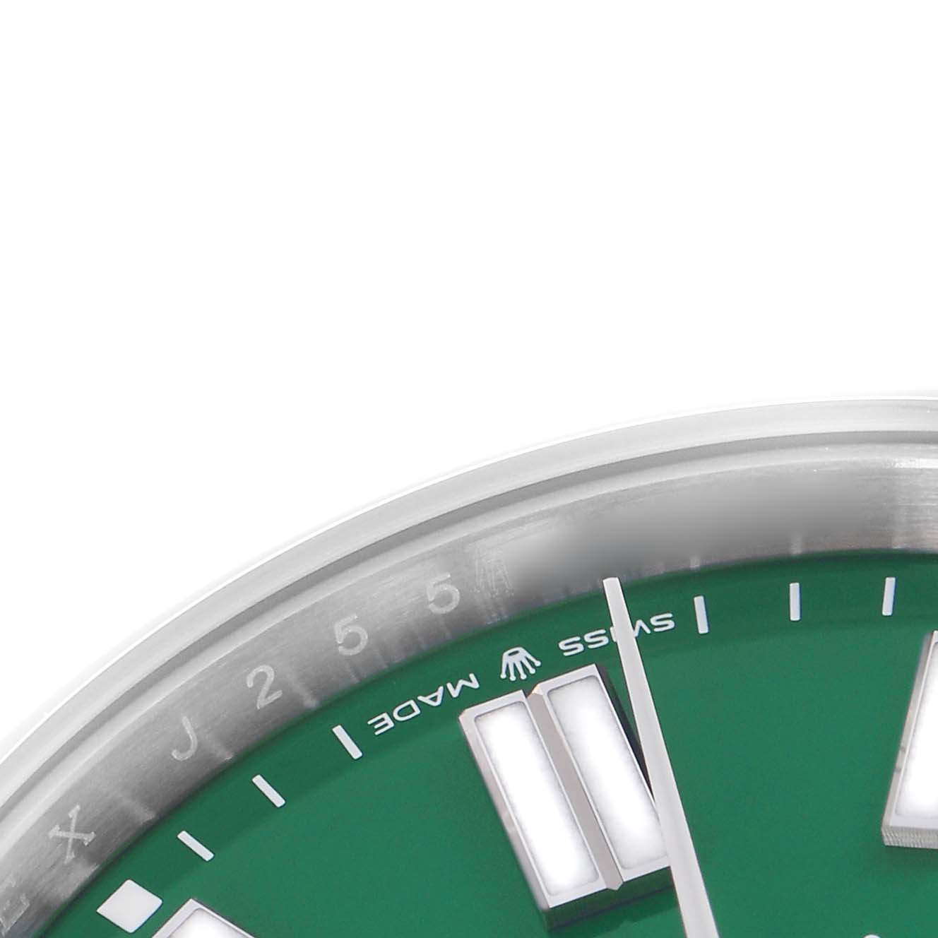 The image shows a close-up of the dial and bezel of a Rolex Oyster Perpetual model 124300, focusing on the green face, hour markers, and the "Swiss Made" text.