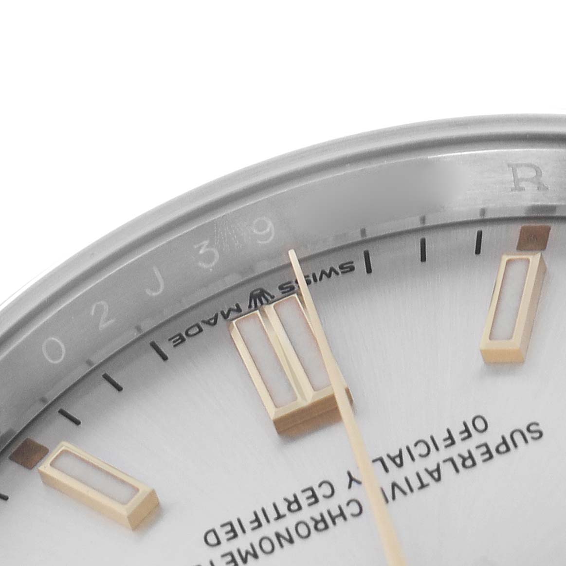 The image shows a close-up of the dial and markers of the Rolex Oyster Perpetual model 126000, highlighting the indices, hands, and a partial view of the "Swiss Made" text.