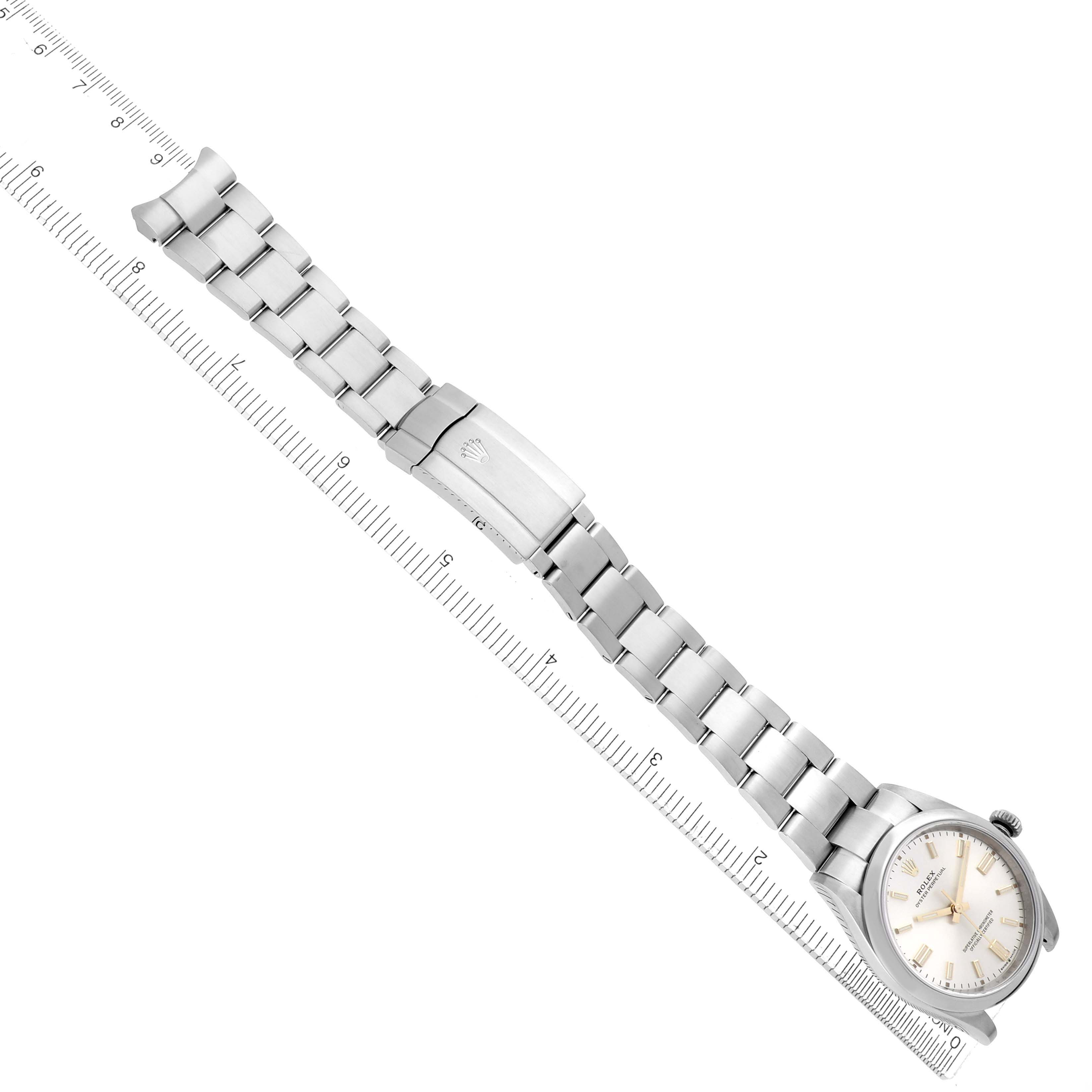 The Rolex Oyster Perpetual model 126000 watch is shown lying flat, highlighting the full bracelet, clasp, and watch face, with a ruler beside for scale.