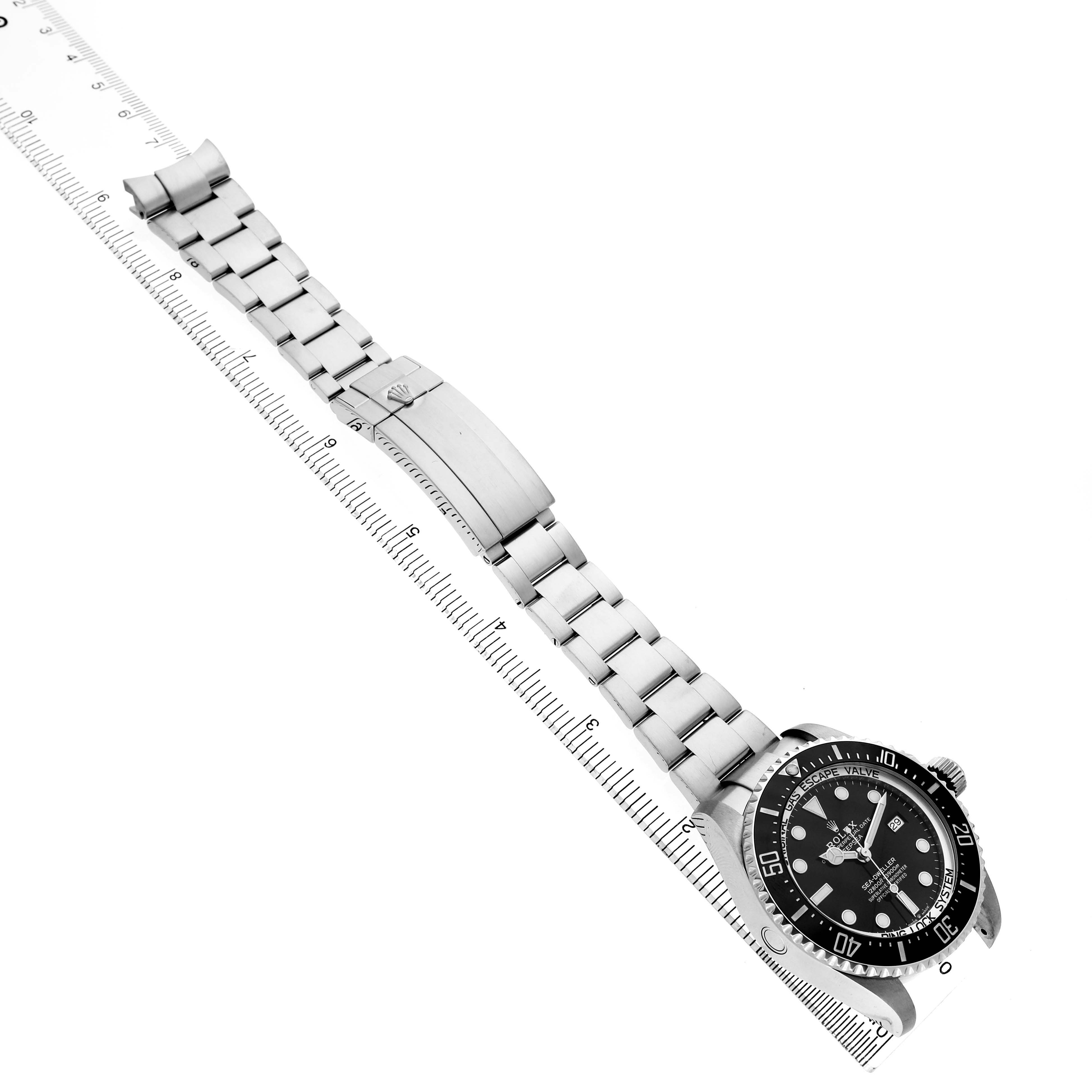 The Rolex Sea-Dweller 126660 Men's Stainless Steel Black Dial watch is shown diagonally, displaying the face, bezel, and full metal bracelet alongside a ruler.