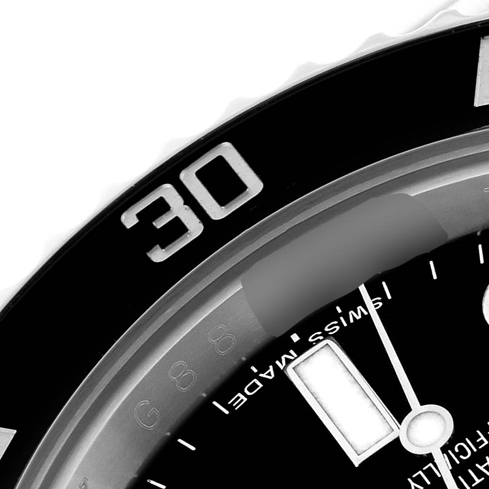 This close-up image of the Rolex Submariner 114060 Men
s Stainless Steel Black Dial 114060 Men
s Stainless Steel Black Dial watch shows the bezel at the 30-minute mark and part of the dial.