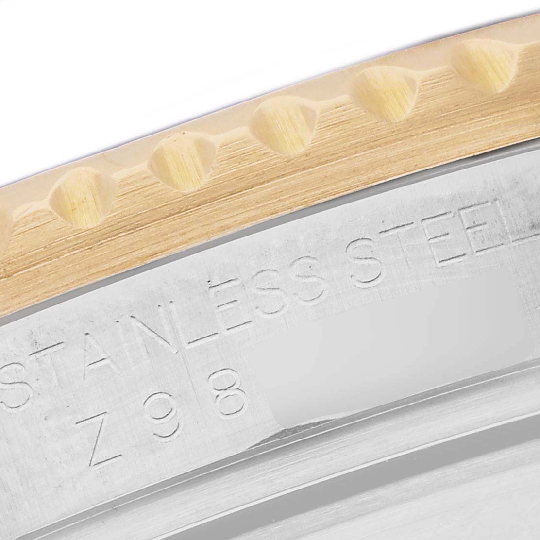 This close-up angle of the Rolex Submariner 16613 Men's Steel and Gold (two tone) Grey Dial 16613 Men's Steel and Gold (two tone) Grey Dial model shows the edge of the bezel and part of the case with "STAINLESS STEEL" engraving.
