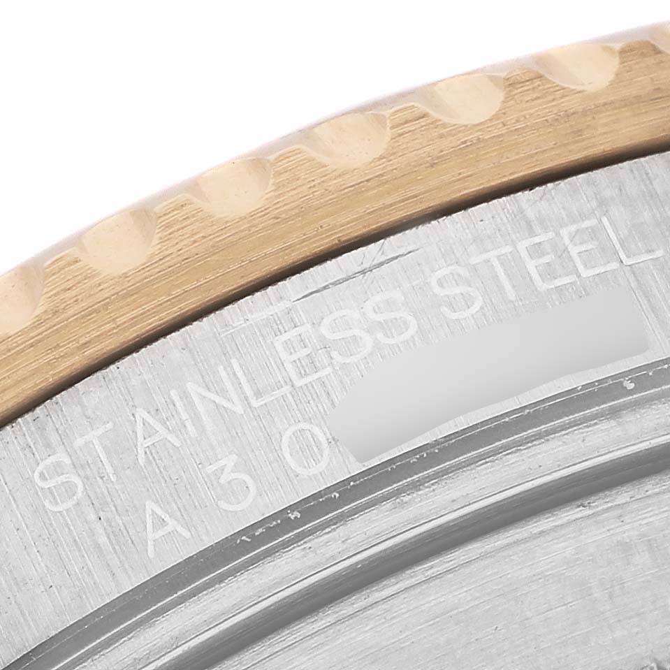 The image shows a close-up of the Rolex Submariner 16613 Men's Steel and Gold (two tone) Champagne Dial's grooved bezel and engraved stainless steel case back.