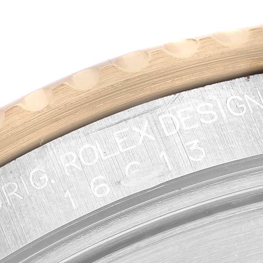 The image shows a close-up of the bezel edge and engraved case of a Rolex Submariner 16613 Men's Steel and Gold (two tone) Champagne Dial watch.