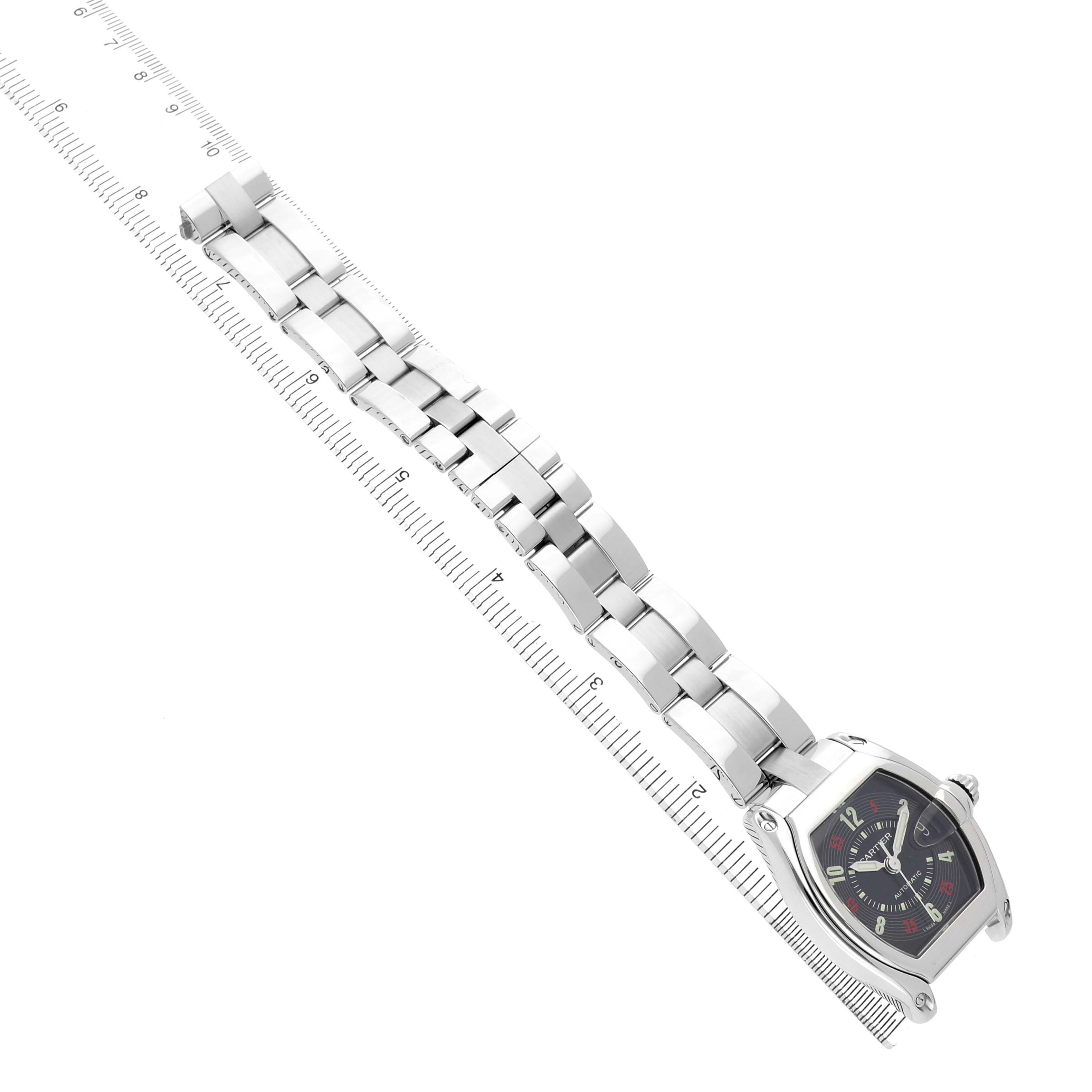 The Cartier Roadster W62002V3 Men's Stainless Steel Black Dial watch is shown at an angled top-down view, highlighting its bracelet and face alongside a measuring ruler.