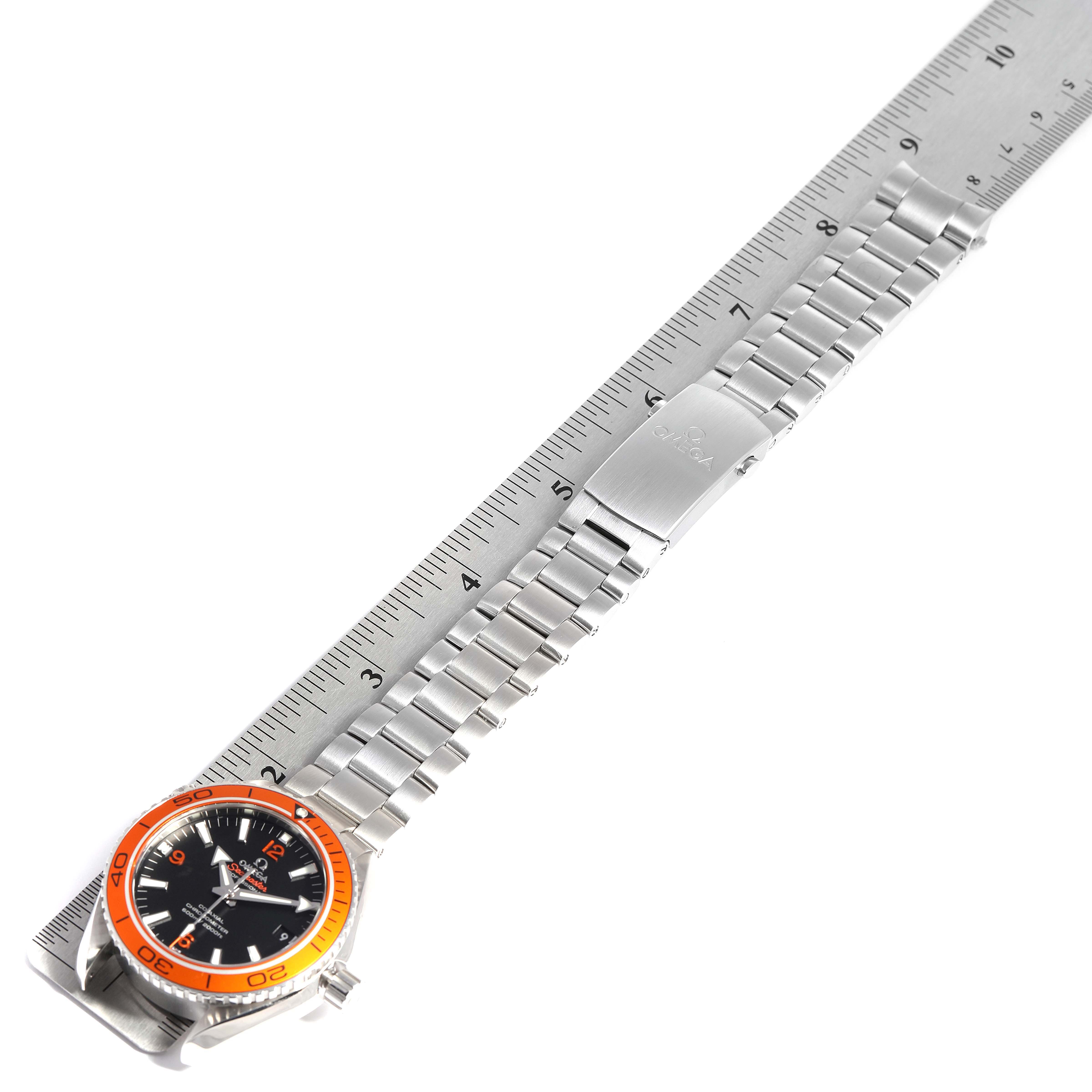 The image shows an Omega Planet Ocean 232.30.42.21.01.002 Men
s Stainless Steel Black Dial 232.30.42.21.01.002 Men
s Stainless Steel Black Dial watch laid flat alongside a ruler, highlighting the stainless steel bracelet and clasp.