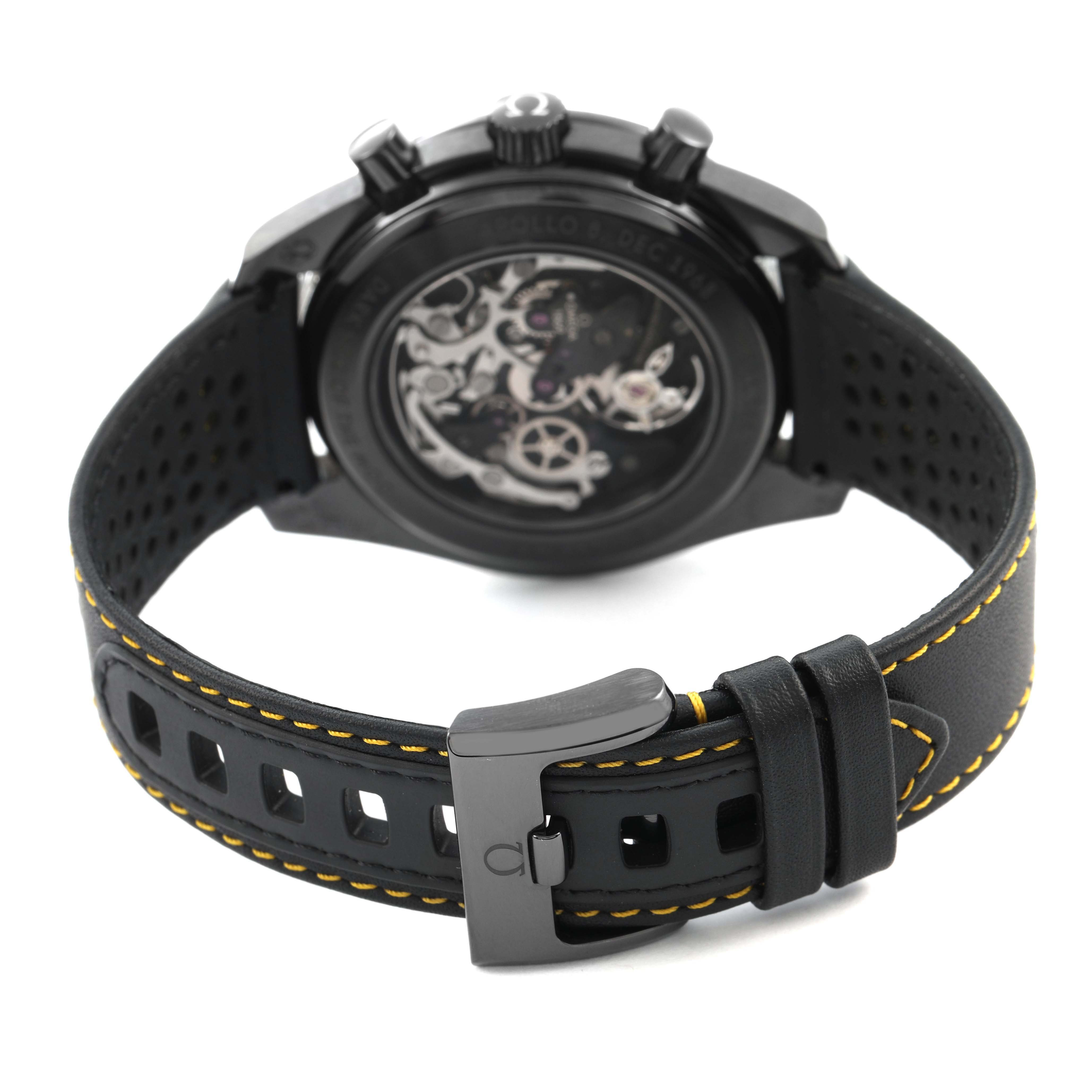 The image shows the back of an Omega Speedmaster 311.92.44.30.01.001 Men's Ceramic Black Dial watch, highlighting the case back and perforated leather strap with yellow stitching.