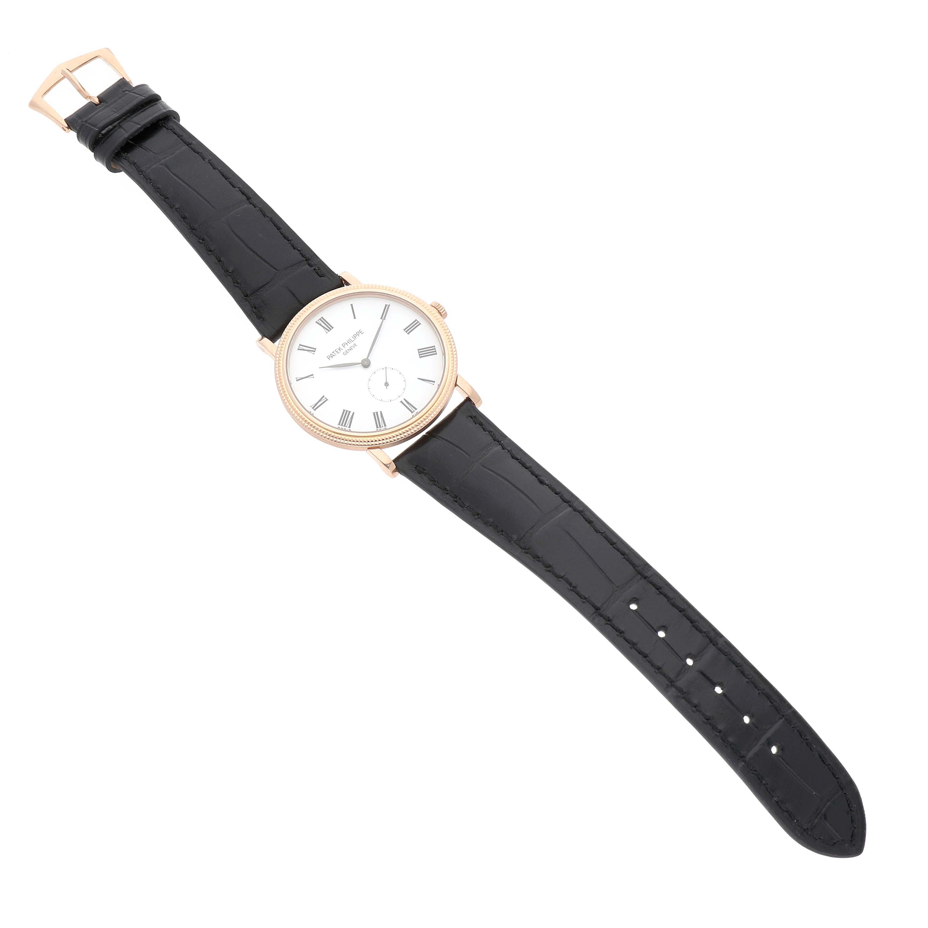 The Patek Philippe Calatrava 5119R Men's Rose Gold White Dial watch is viewed from above, showing its round face, leather strap, and buckle.