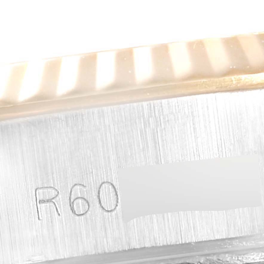 This image shows a close-up of the serial number engraving and part of the fluted bezel on a Rolex Datejust 69173 Women
s Steel and Gold (two tone) Champagne Dial 69173 Women
s Steel and Gold (two tone) Champagne Dial watch.