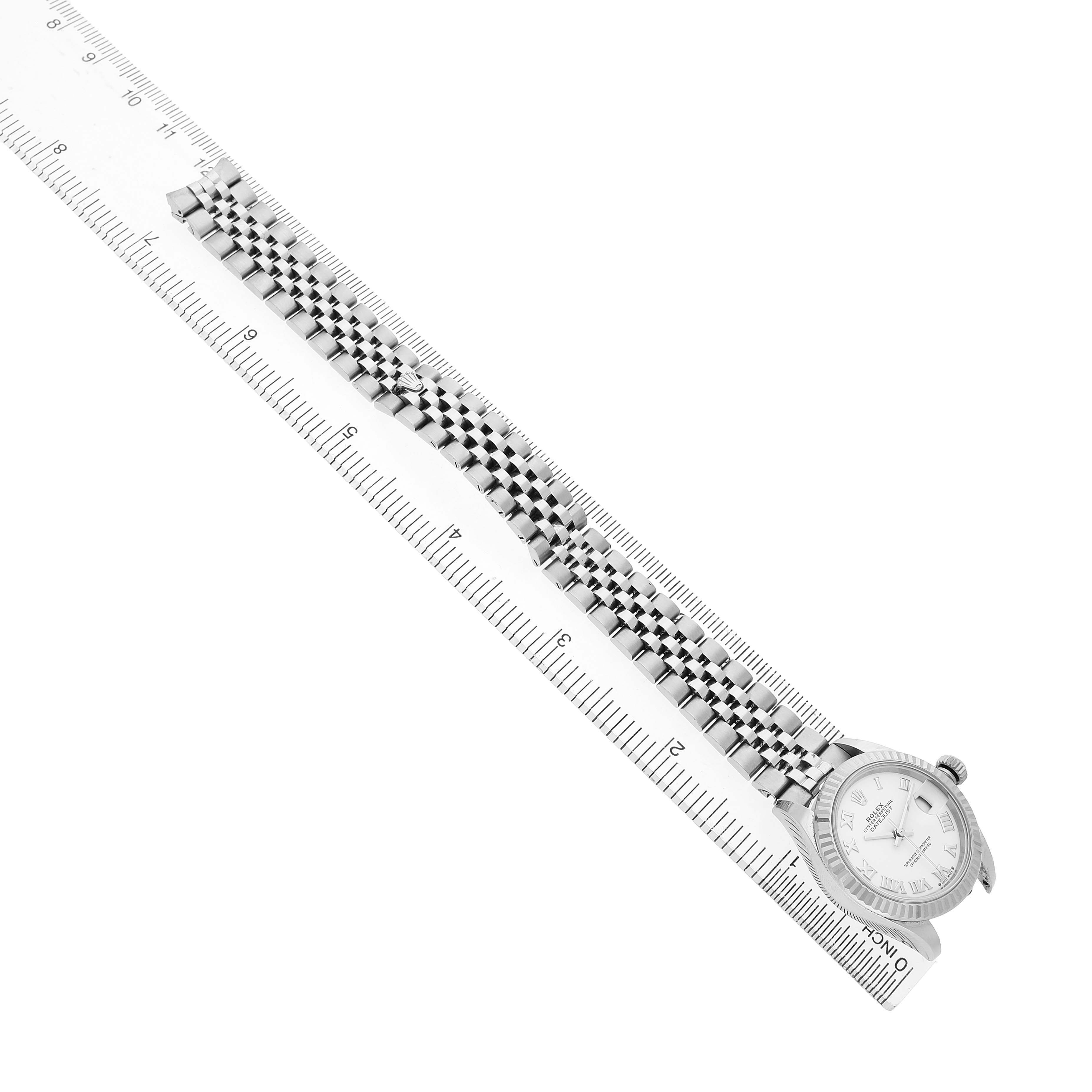 The Rolex Datejust 279174 Women's Stainless Steel White Dial watch is shown at an angle, displaying its face, bezel, and full bracelet alongside a ruler.