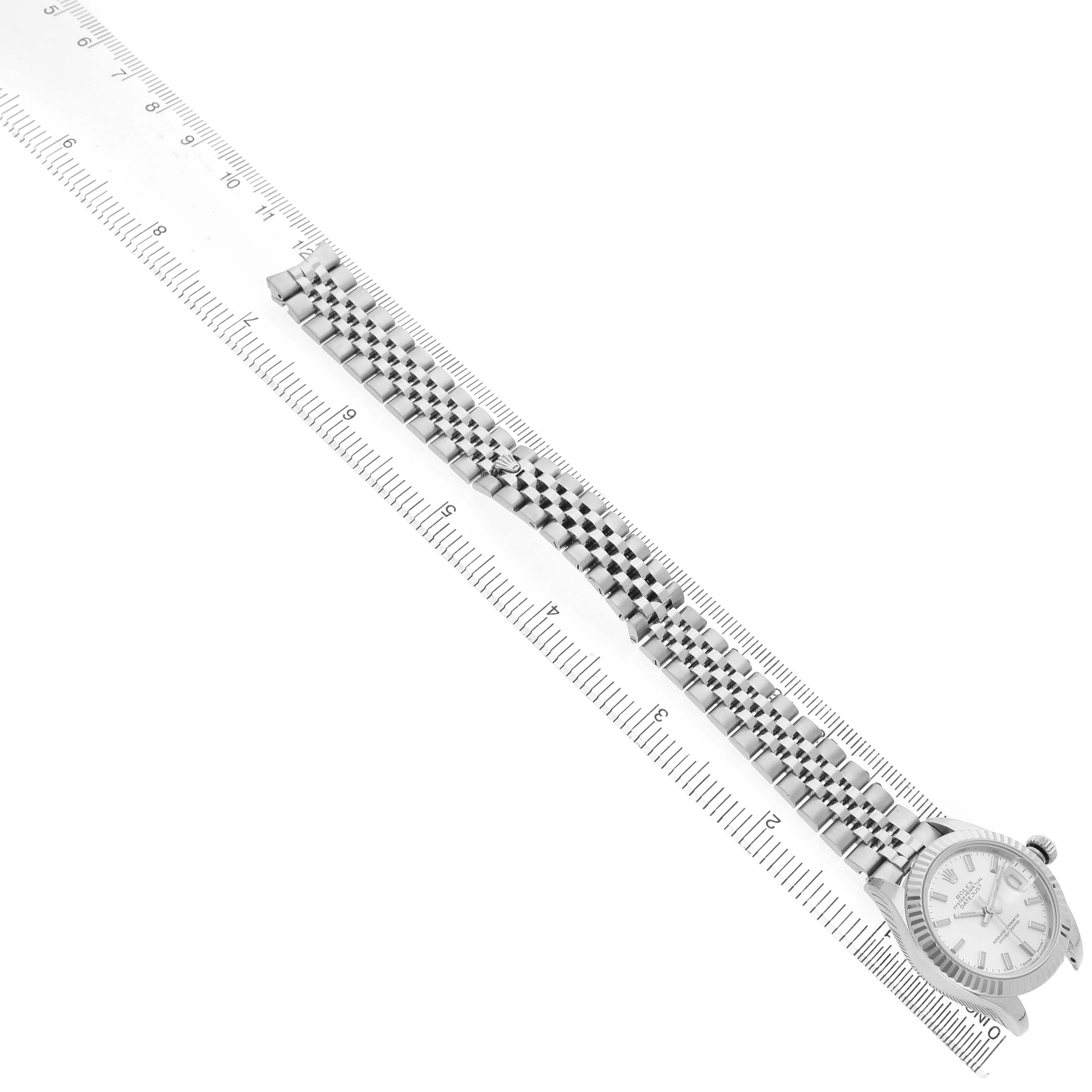 The Rolex Datejust 279174 Women's Stainless Steel Silver Dial watch is shown from a top view, highlighting the face, bezel, and jubilee bracelet alongside a ruler.