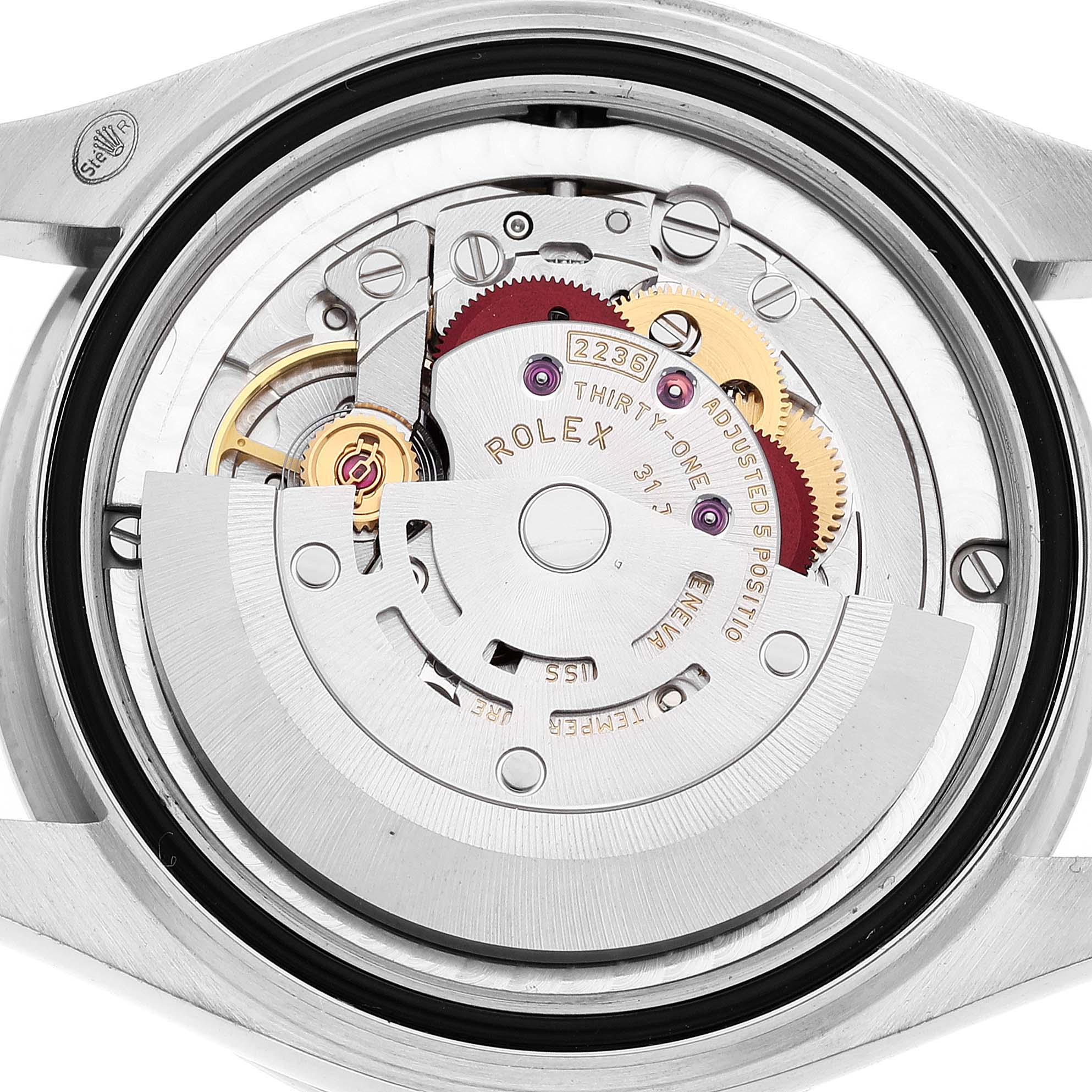 The image shows the open case back of a mid-size Rolex watch, displaying its internal movement components.
