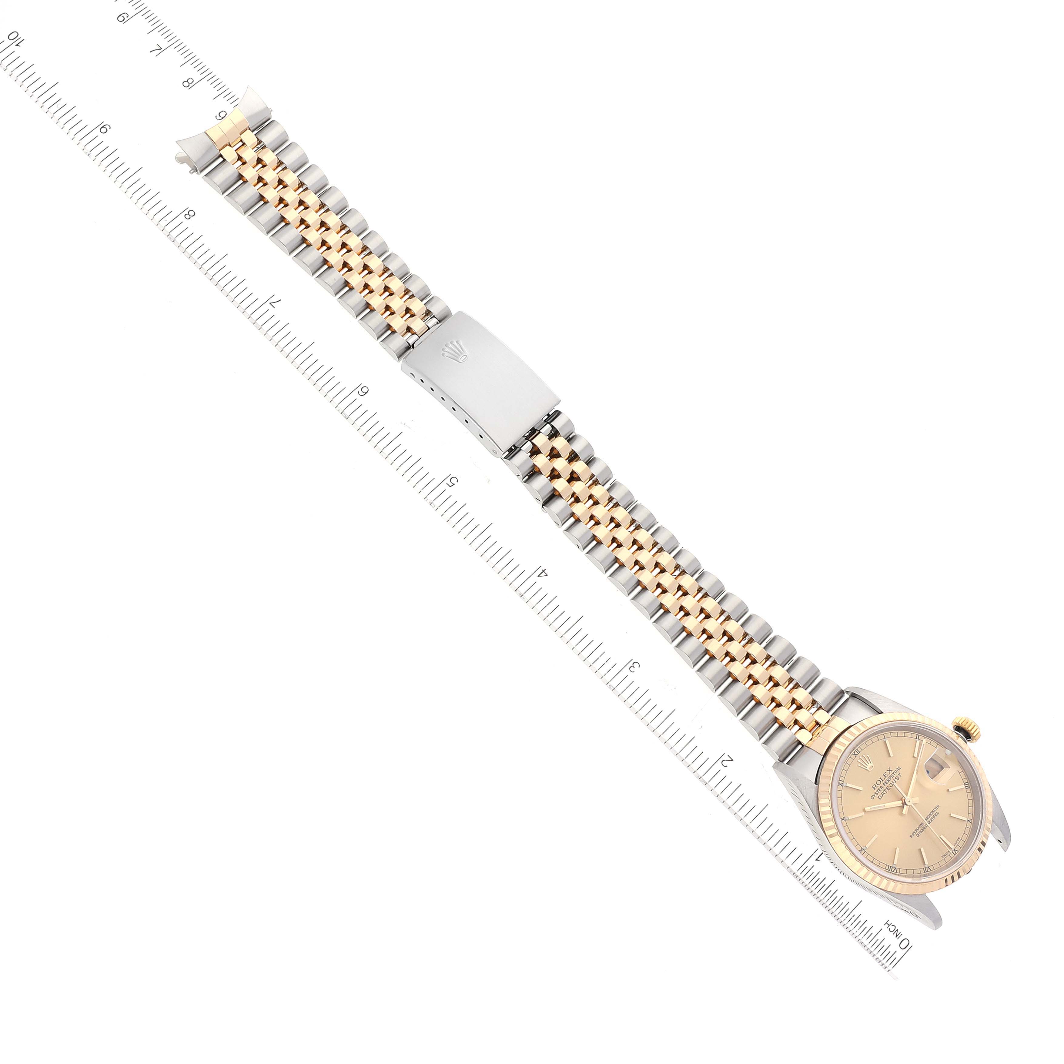 The image shows a Rolex Datejust 16233 Men's Steel and Gold (two tone) Champagne Dial 16233 Men's Steel and Gold (two tone) Champagne Dial watch with its full strap and face, positioned diagonally against a ruler for scale.